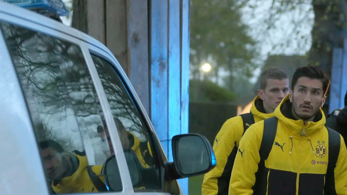 ARCHIV - Spieler von Borussia Dortmund, darunter Sven Bender (l-r) und Nuri Sahin, und Polizisten stehen am 11.04.2017 in Dortmund (Nordrhein-Westfalen) vor einem Hotel. Kurz nach der Abfahrt der Mannschaft von Dortmund vom Hotel zum Stadion sind in der Nähe des Mannschaftsbusses drei Sprengsätze explodiert. (zu dpa «Nuri Sahin will Anschlag auf Borussia Dortmund nicht verdrängen» vom 19.04.2017) Foto: Ina Fassbender/dpa +++(c) dpa - Bildfunk+++