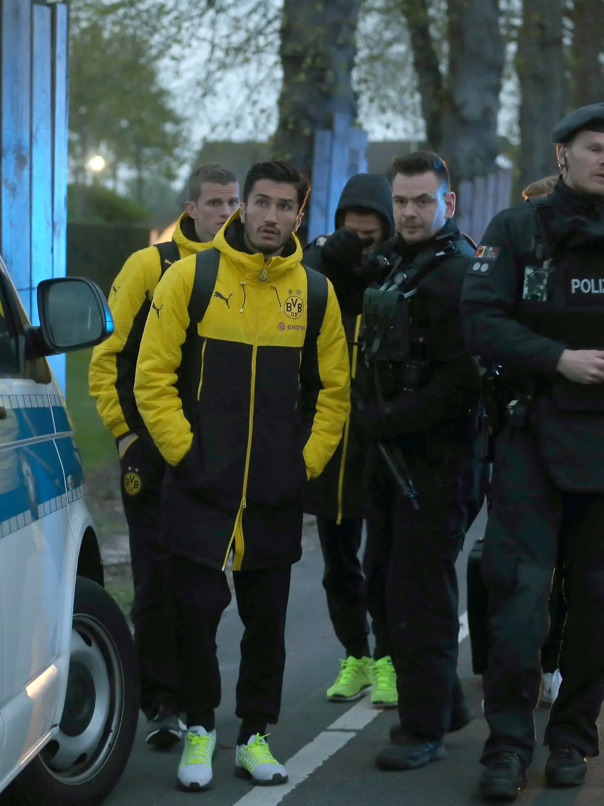 ARCHIV - Spieler von Borussia Dortmund, darunter Sven Bender (l-r) und Nuri Sahin, und Polizisten stehen am 11.04.2017 in Dortmund (Nordrhein-Westfalen) vor einem Hotel. Kurz nach der Abfahrt der Mannschaft von Dortmund vom Hotel zum Stadion sind in der Nähe des Mannschaftsbusses drei Sprengsätze explodiert. (zu dpa «Nuri Sahin will Anschlag auf Borussia Dortmund nicht verdrängen» vom 19.04.2017) Foto: Ina Fassbender/dpa +++(c) dpa - Bildfunk+++