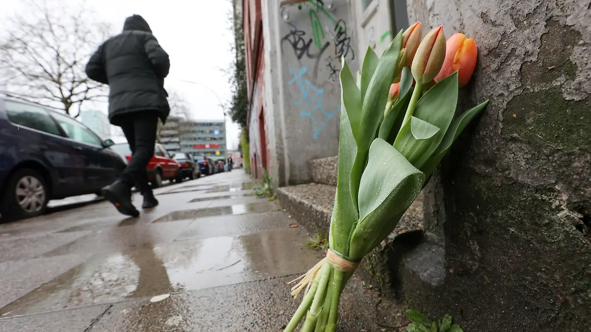 05.04.2022, Hamburg: Blumen liegen vor einem Mehrfamilienhaus, aus dem zuvor zwei Leichen abtransportiert wurden. In einem Haus nahe dem Bahnhof Hamburg-Altona sind am Dienstagmorgen Schüsse gefallen. Die Polizei fand zwei leblose Personen. Es gebe keine weiteren Beteiligten, sagte die Polizei. Sie geht darum von einem sogenannten erweiterten Suizid aus. Foto: Bodo Marks/dpa +++ dpa-Bildfunk +++