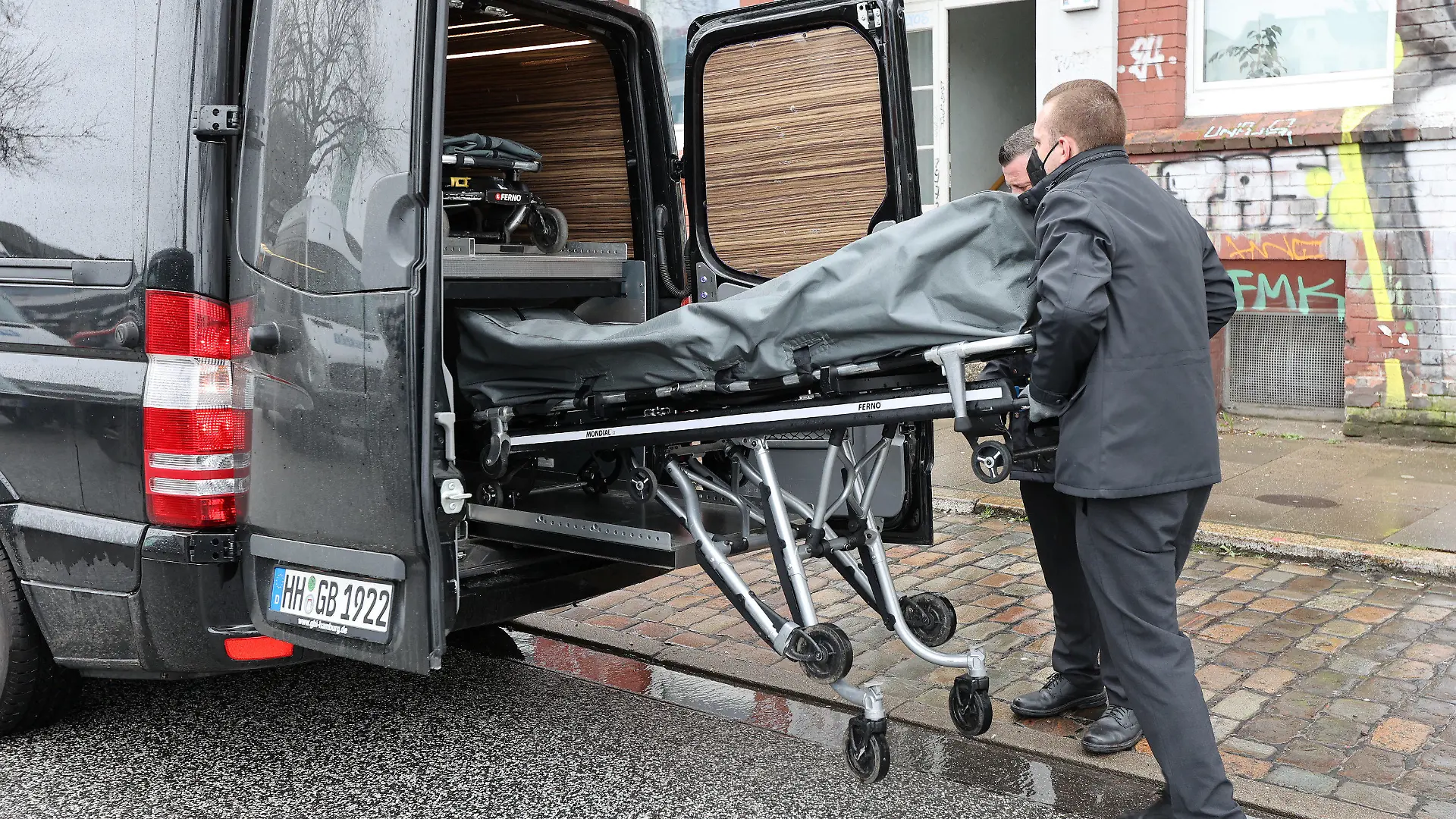 05.04.2022, Hamburg: Zwei Bestatter verbringen eine von zwei Leichen aus einem Mehrfamilienhaus in den Leichenwagen. In einem Haus nahe dem Bahnhof Hamburg-Altona sind am Dienstagmorgen Schüsse gefallen. Die Polizei fand zwei leblose Personen. Es gebe keine weiteren Beteiligten, sagte die Polizei. Sie geht darum von einem sogenannten erweiterten Suizid aus. Foto: Bodo Marks/dpa +++ dpa-Bildfunk +++