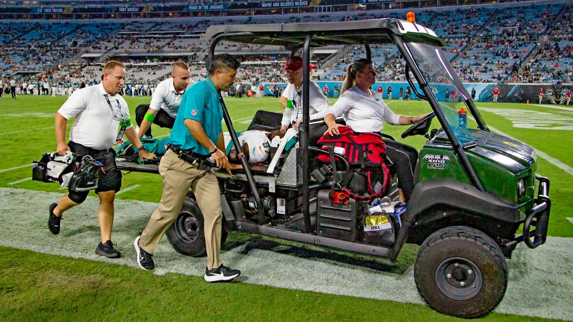 26.08.2023, USA, Jacksonville: American Football: Profiliga NFL, Vorsaison, Jacksonville Jaguars - Miami Dolphins. Wide Receiver Daewood Davis (87) von den Miami Dolphins wird während des Vorbereitungsspiels vom Spielfeld getragen. In der NFL ist knapp zwei Wochen vor dem Saisonstart erneut ein Testspiel nach der Verletzung eines Football-Profis abgebrochen worden. Daewood Davis von den Miami Dolphins blieb nach einem harten Zusammenprall in der Partie gegen die Jacksonville Jaguars am Samstag (Ortszeit) minutenlang mit dem Gesicht auf dem Boden liegen. Foto: Al Diaz/Miami Herald/AP/dpa - ACHTUNG: Nur zur redaktionellen Verwendung und nur mit vollständiger Nennung des vorstehenden Credits +++ dpa-Bildfunk +++