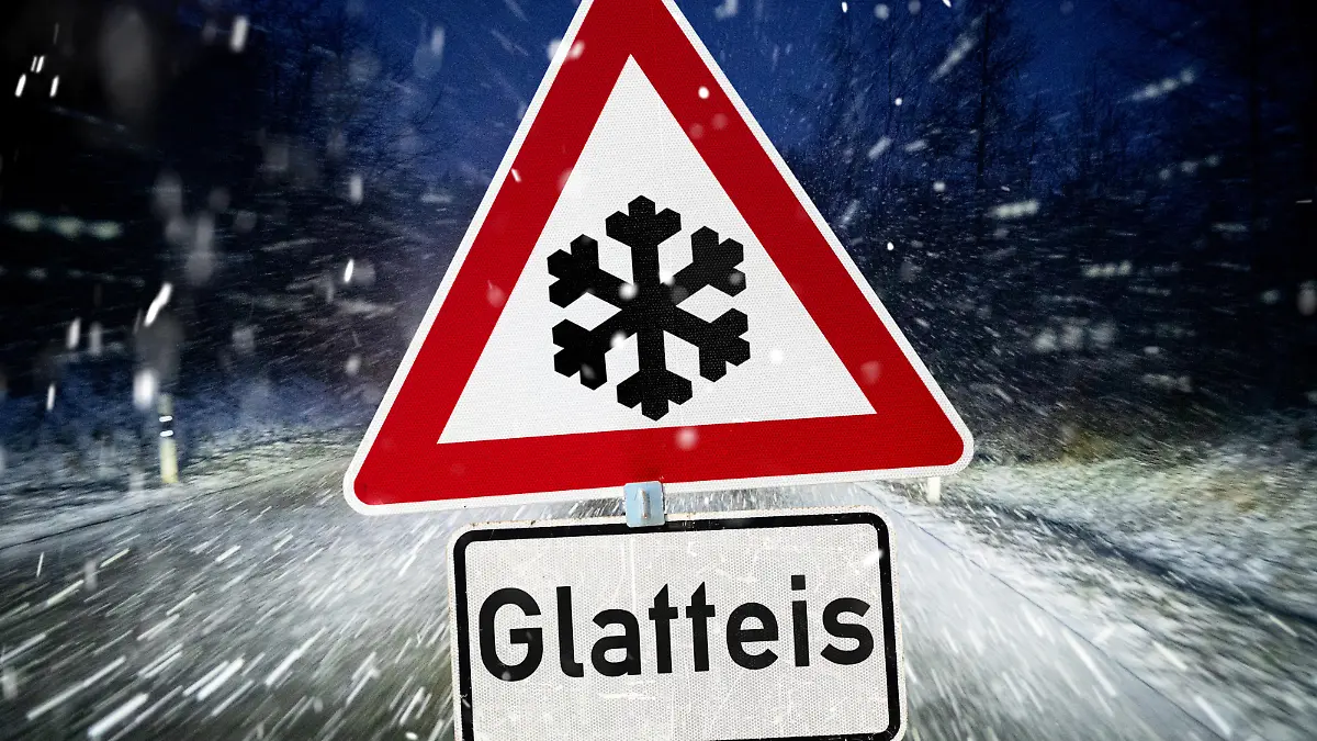 January 22, 2025: A traffic sign warns of black ice on wintry roads with heavy snowfall and freezing temperatures at night. PHOTOMONTAGE *** Ein Verkehrsschild warnt vor Glatteis auf winterlichen Straßen bei dichtem Schneefall und eisigen Temperaturen in der Nacht. FOTOMONTAGE