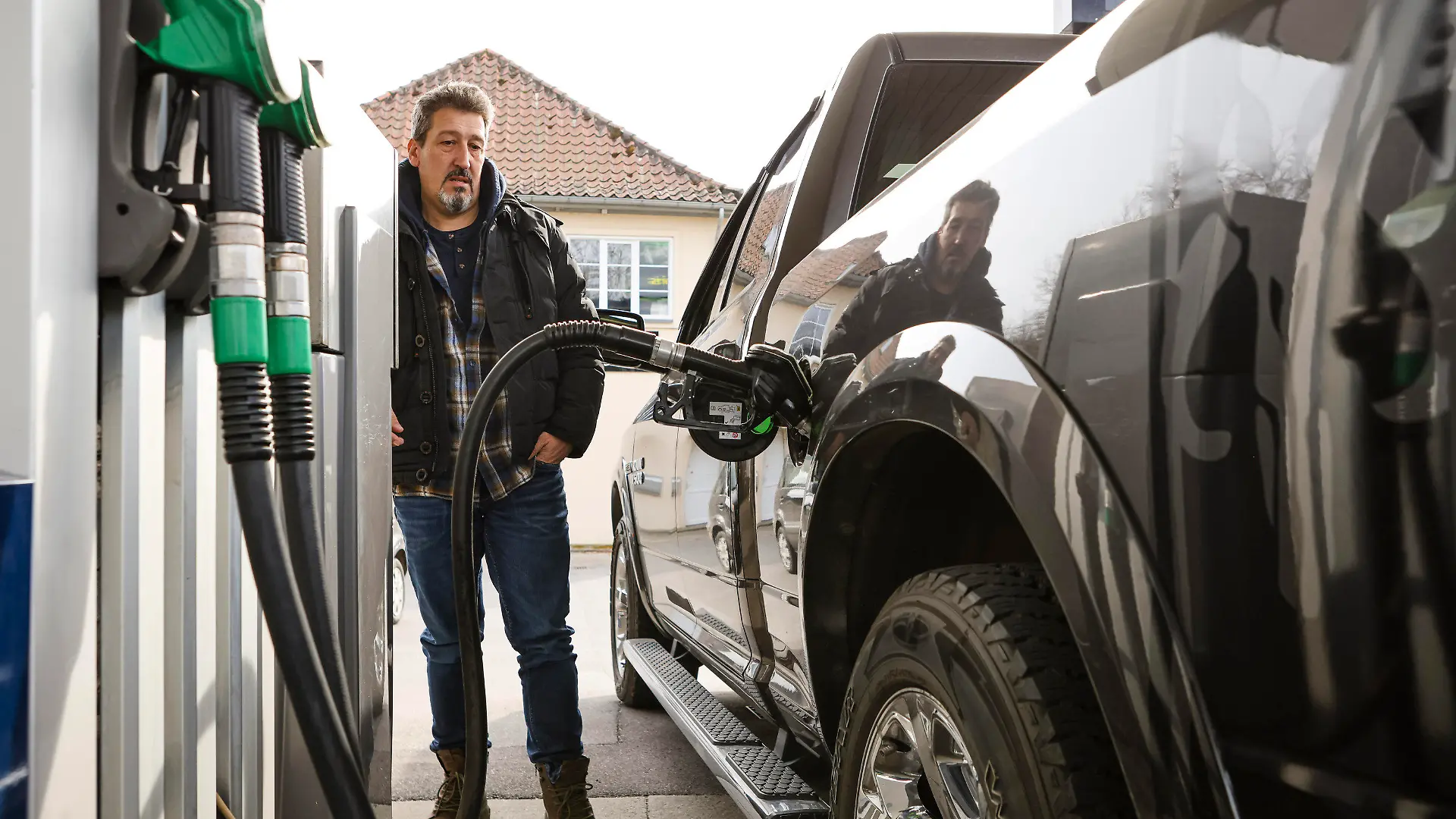 PRODUKTION - 14.03.2022, Dänemark, Kruså: Guido Matt aus Flensburg betankt seinen 100 Liter fassenden Geländewagen an einer dänischen Tankstelle. Zum Tanken über die Grenze zu fahren, kann sich derzeit lohnen. Benzin und Diesel sind in Dänemark aktuell bis zu 50 Cent pro Liter günstiger. Foto: Frank Molter/dpa +++ dpa-Bildfunk +++