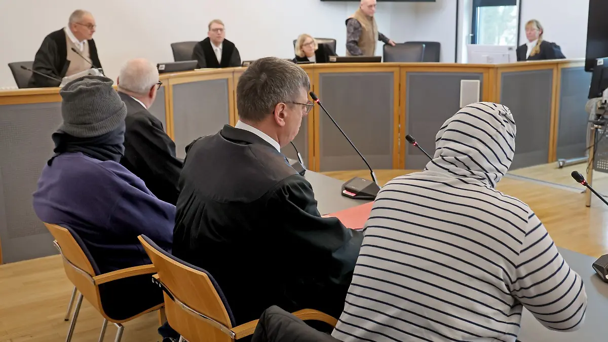 Mit Mütze, Schal und Kapuzen-Pulli auf der Anklagebank.