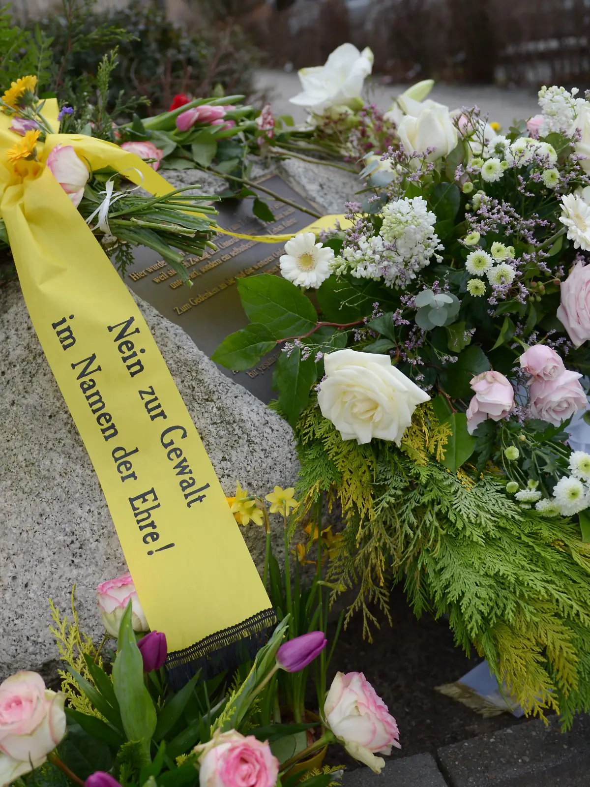 Kränze und Blumen liegen am 07.02.2013 am Gedenkstein für Hatun Sürücü an einer Bushaltestelle in der Oberlandstraße in Berlin. Die aus einer streng muslimischen Familie stammende Sürücü war am 7. Februar 2005 einem sogenannten Ehrenmord zum Opfer gefallen. Foto: Rainer Jensen/dpa ++