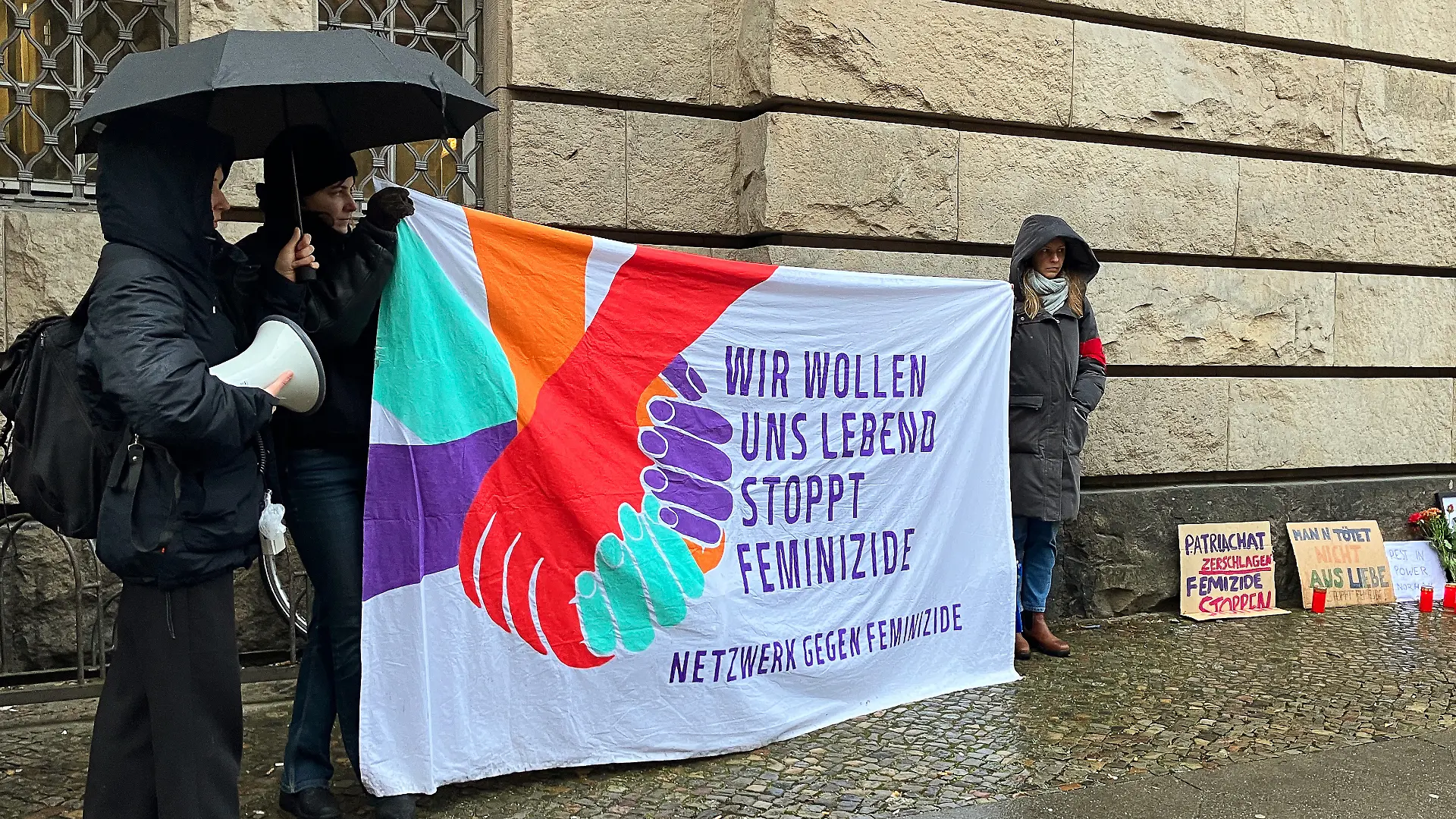 Eine kleine Gruppe steht vor dem Eingang des Kriminalgerichts in Moabit und demonstriert.