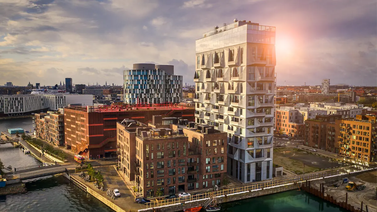 HDR image of Copenhagen cityscape with contemporary office buildings and residental flats at the up class oceanfront, Nordhavn, shot with drone. Dramatic cloudscape and lens flare in background.