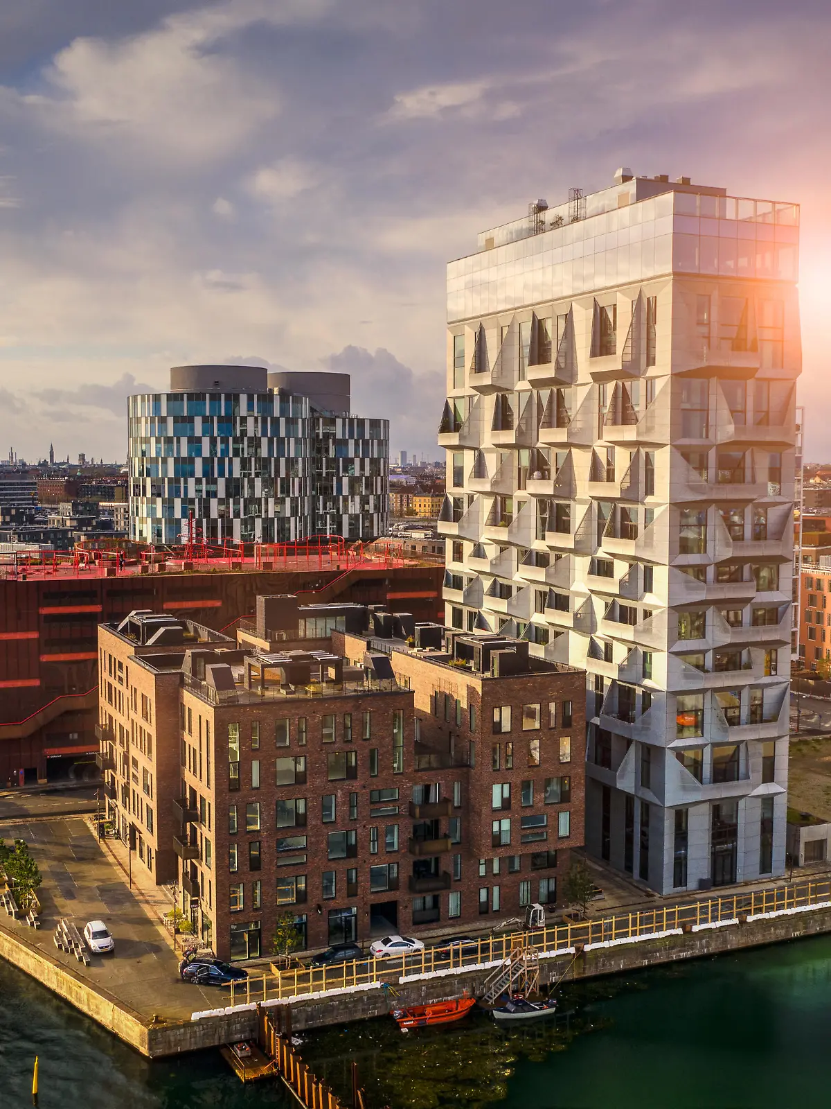 HDR image of Copenhagen cityscape with contemporary office buildings and residental flats at the up class oceanfront, Nordhavn, shot with drone. Dramatic cloudscape and lens flare in background.