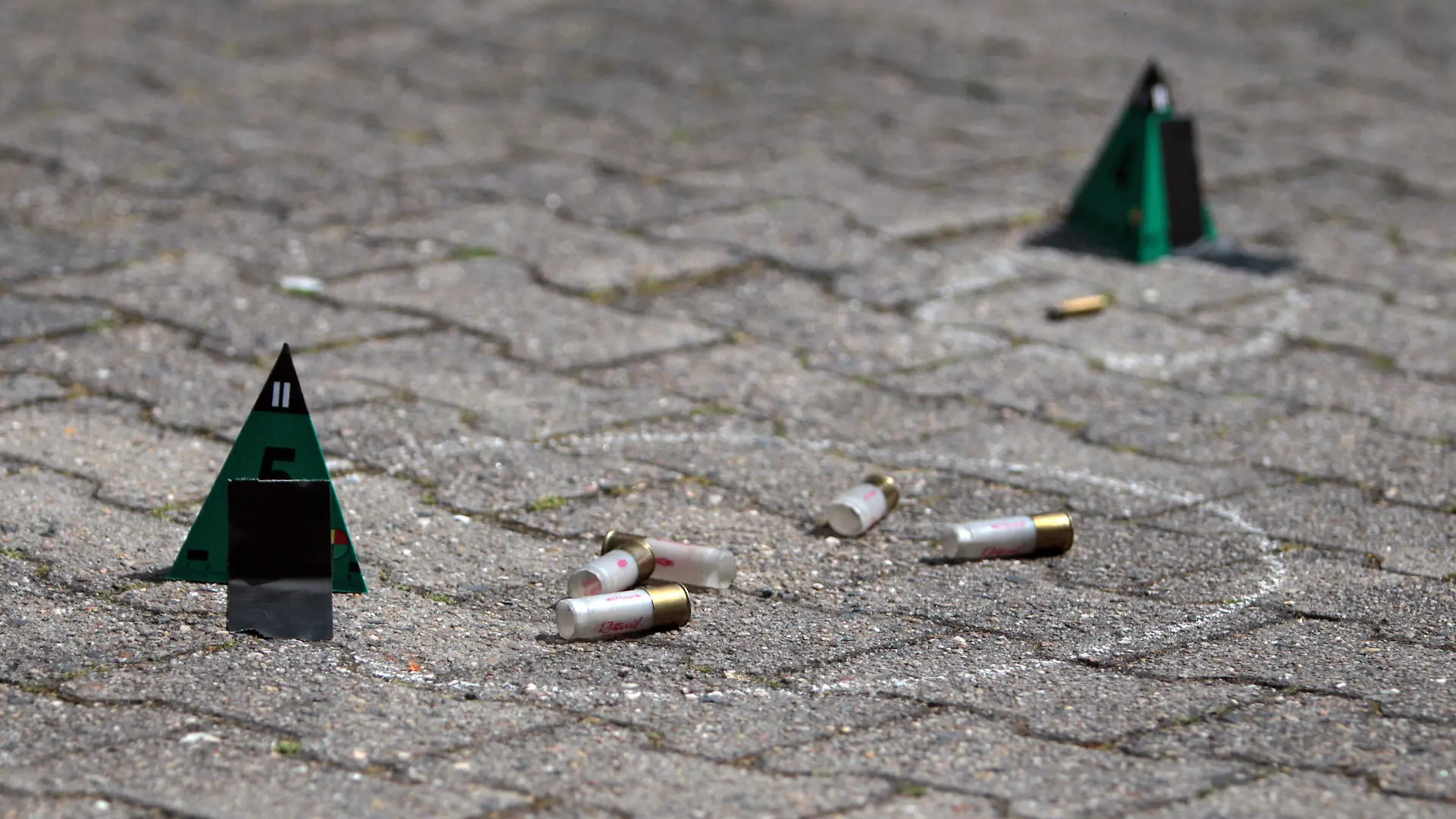An der Stelle, an der zuvor ein Mann erschossen worden ist, liegen am 17.05.2015 am Tatort in Rodgau (Hessen) Polizei-Markierungen an Patronenhülsen und Einschusslöchern. Bei einem Polizeieinsatz in Rodgau (Kreis Offenbach) ist am Sonntagmorgen ein 74-Jähriger getötet worden. Laut dem Landeskriminalamt (LKA) Wiesbaden habe der Mann zuvor auf die Einsatzkräfte geschossen, um seine Einweisung in eine Klinik zu verhindern. Mehrere Beamte eines Spezialeinsatzkommandos (SEK) schossen zurück und verletzten den Mann tödlich. Foto: Fredrik von Erichsen/dpa +++(c) dpa - Bildfunk+++