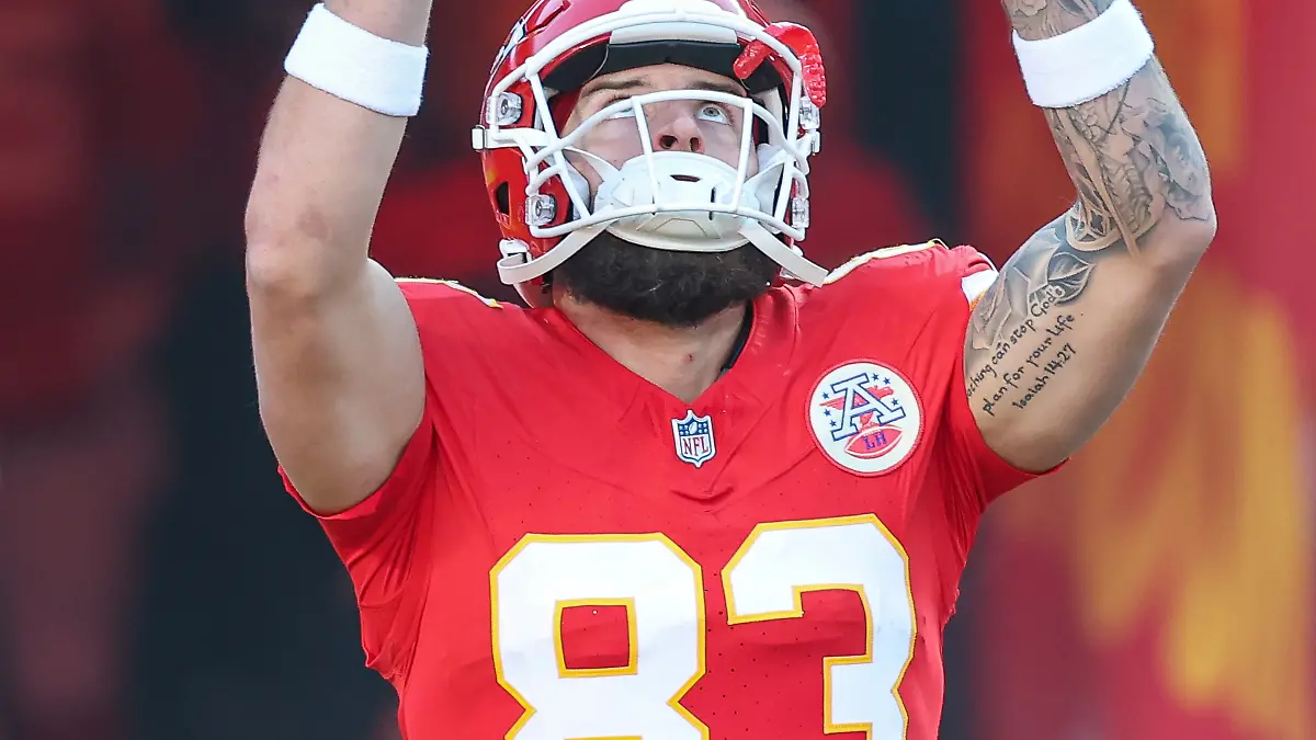Ein Spieler der Kansas City Chiefs mit Trikot und Helm auf dem Spielfeld hebt beide Hände zum Himmel.