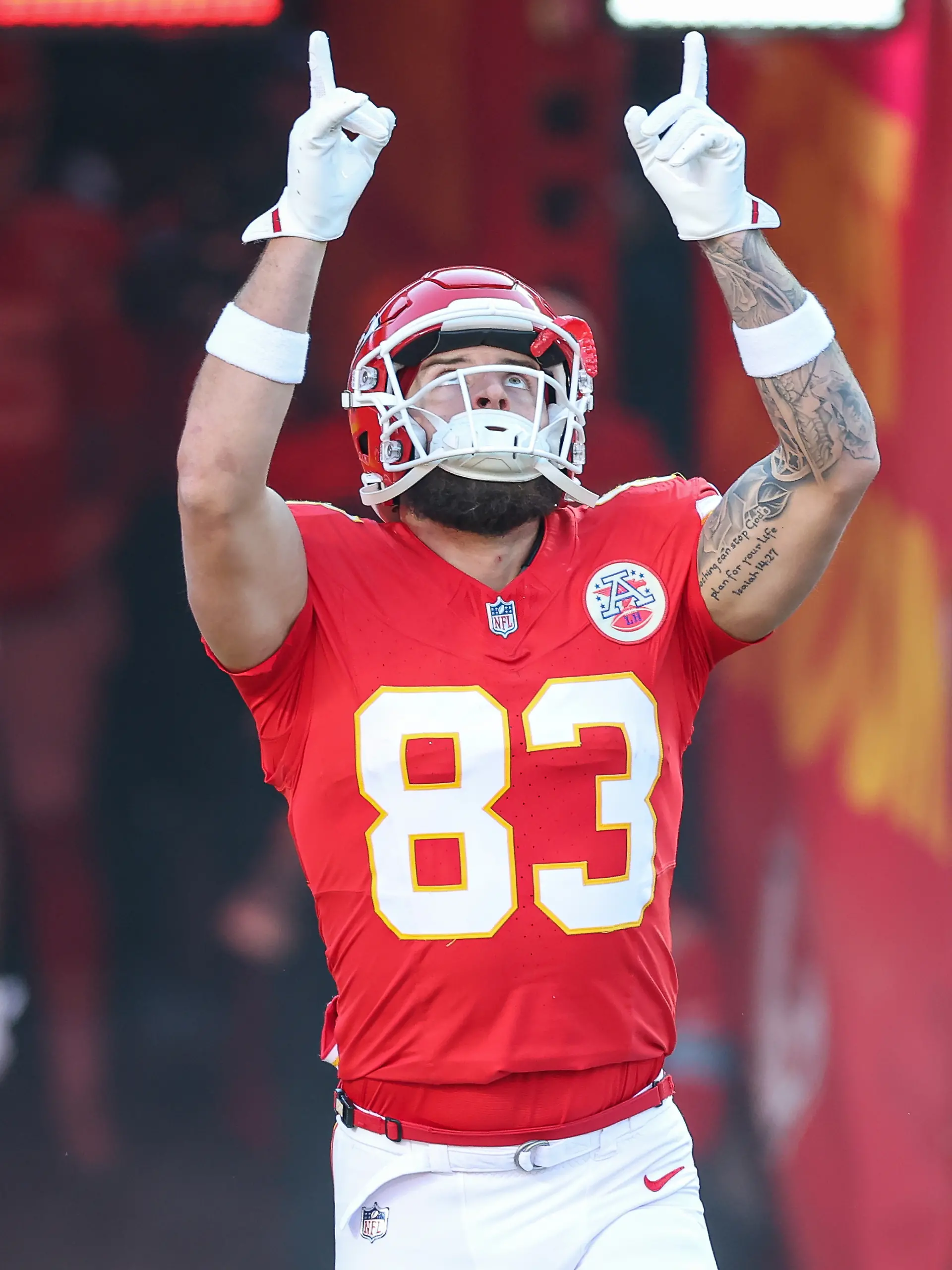 Ein Spieler der Kansas City Chiefs mit Trikot und Helm auf dem Spielfeld hebt beide Hände zum Himmel.