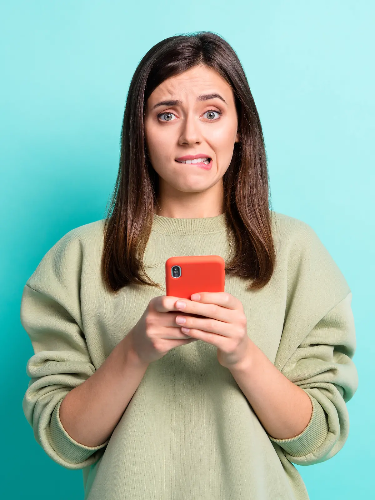 Frau schaut entsetzt in die Kamera und hält ein Handy in der Hand, während sie vor einem blauen Hintergrund steht