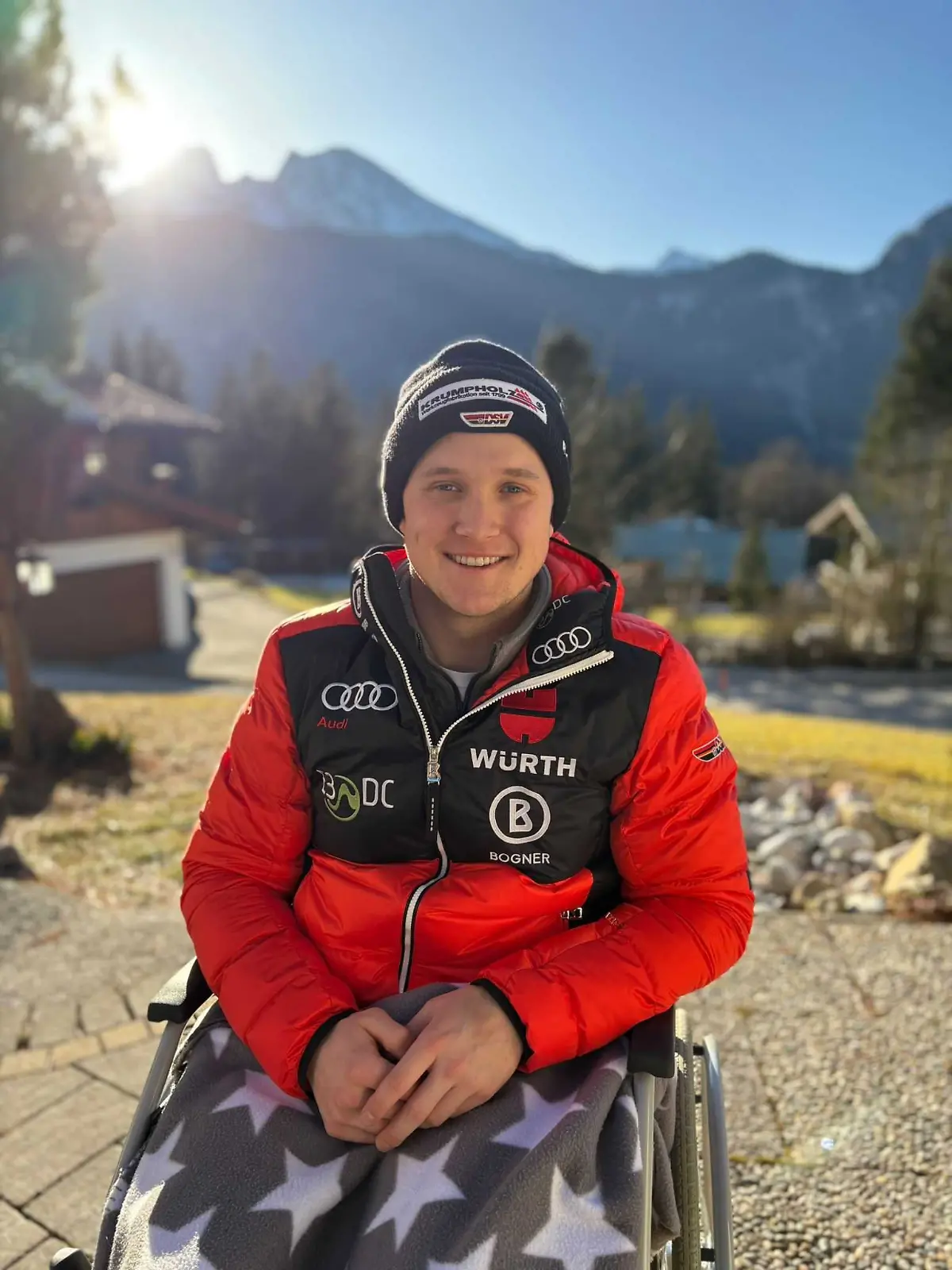 Jacob Schramm, Alpiner-Skirennläufer, sitzt vor einer Bergkulisse im Rollstuhl
