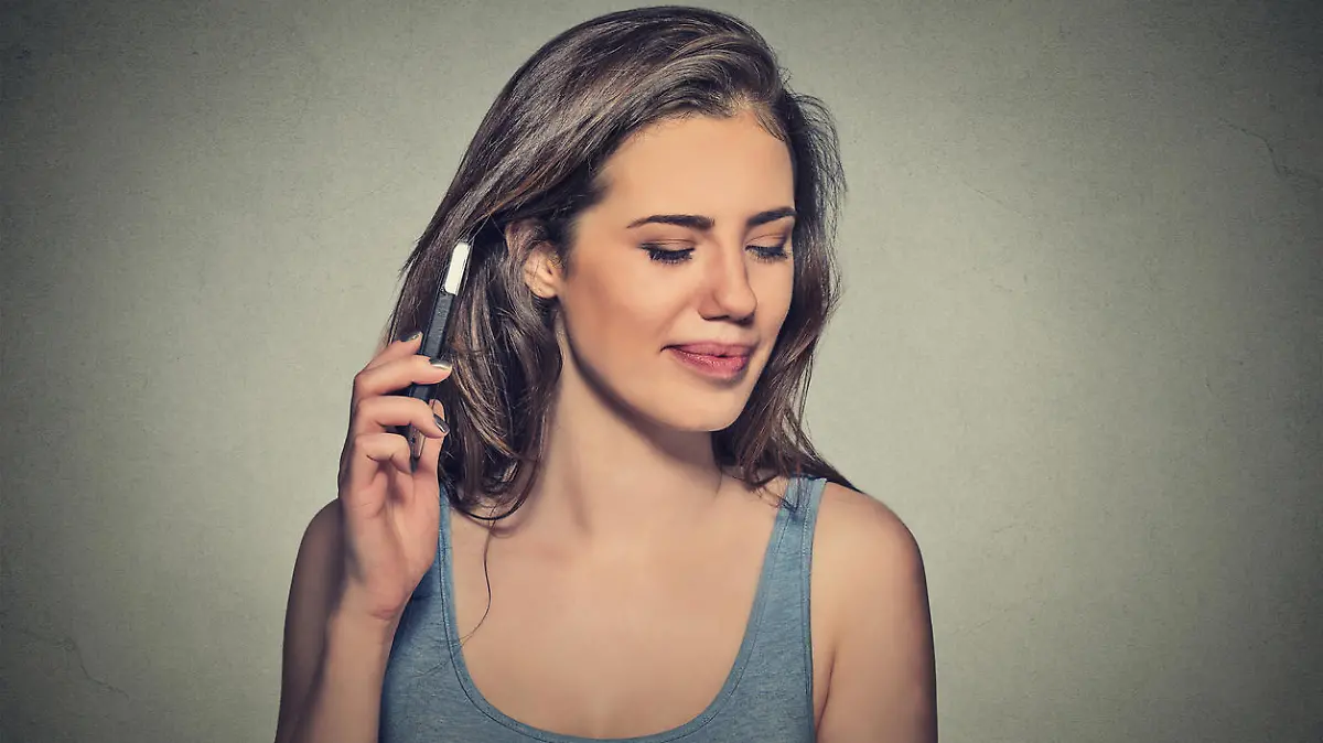 young woman displeased on phone with headache. Upset unhappy girl talking on phone isolated gray background. Negative human emotion face expression feeling life reaction. Cellular radiation concept