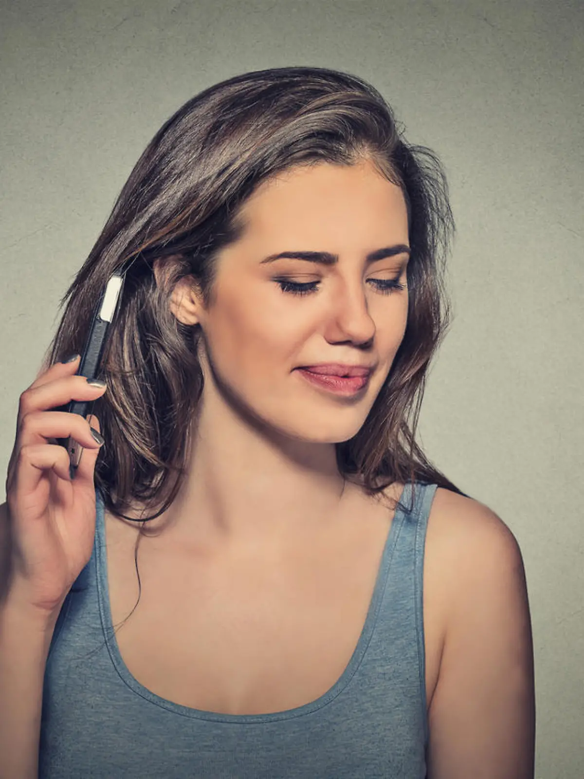 young woman displeased on phone with headache. Upset unhappy girl talking on phone isolated gray background. Negative human emotion face expression feeling life reaction. Cellular radiation concept
