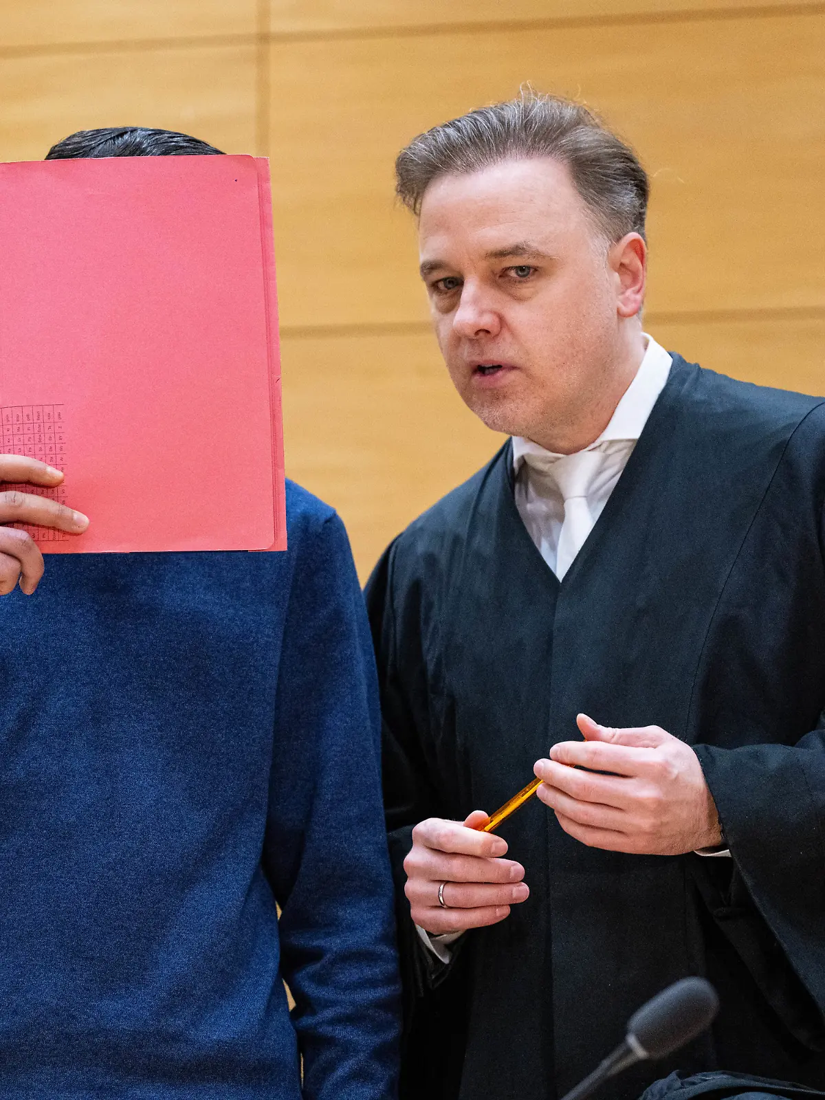 Einer der Angeklagten (l.) steht mit seinem Anwalt Burkhard Benecken beim Beginn des Prozesses um den Totschlag nach einer Abifeier in Bad Oeynhausen vor dem Landgericht. Angeklagt sind drei Männer. (zu dpa: «Aussage angekündigt: Prozess um Tod nach Abifeier in Bad Oeynhausen») Foto: Guido Kirchner/dpa +++ dpa-Bildfunk +++