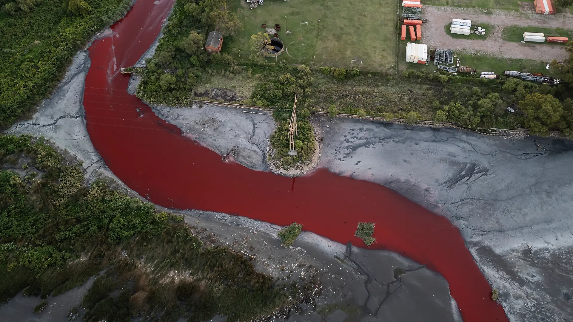06.02.2025, Argentinien, Buenos Aires: Eine Luftaufnahme zeigt den «Sarandí»-Fluss in einem Industriegebiet am Rande von Buenos Aires, dessen Wasser sich intensiv rot verfärbt hat. Anwohner vermuten, dass unbekannte Schadstoffe für die auffällige Färbung verantwortlich sind. Das Umweltministerium hat Wasserproben entnommen, um die Ursache der Verfärbung zu ermitteln Foto: Rodrigo Abd/AP/dpa +++ dpa-Bildfunk +++