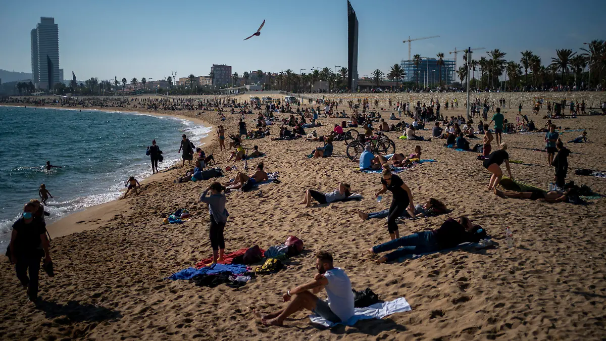 01.11.2020, Spanien, Barcelona: Menschen sonnen sich mit Abstand voneinander am Strand. Spanien ist eines der von der Corona-Krise am schwersten getroffenen Länder Westeuropas. Foto: Emilio Morenatti/AP/dpa +++ dpa-Bildfunk +++