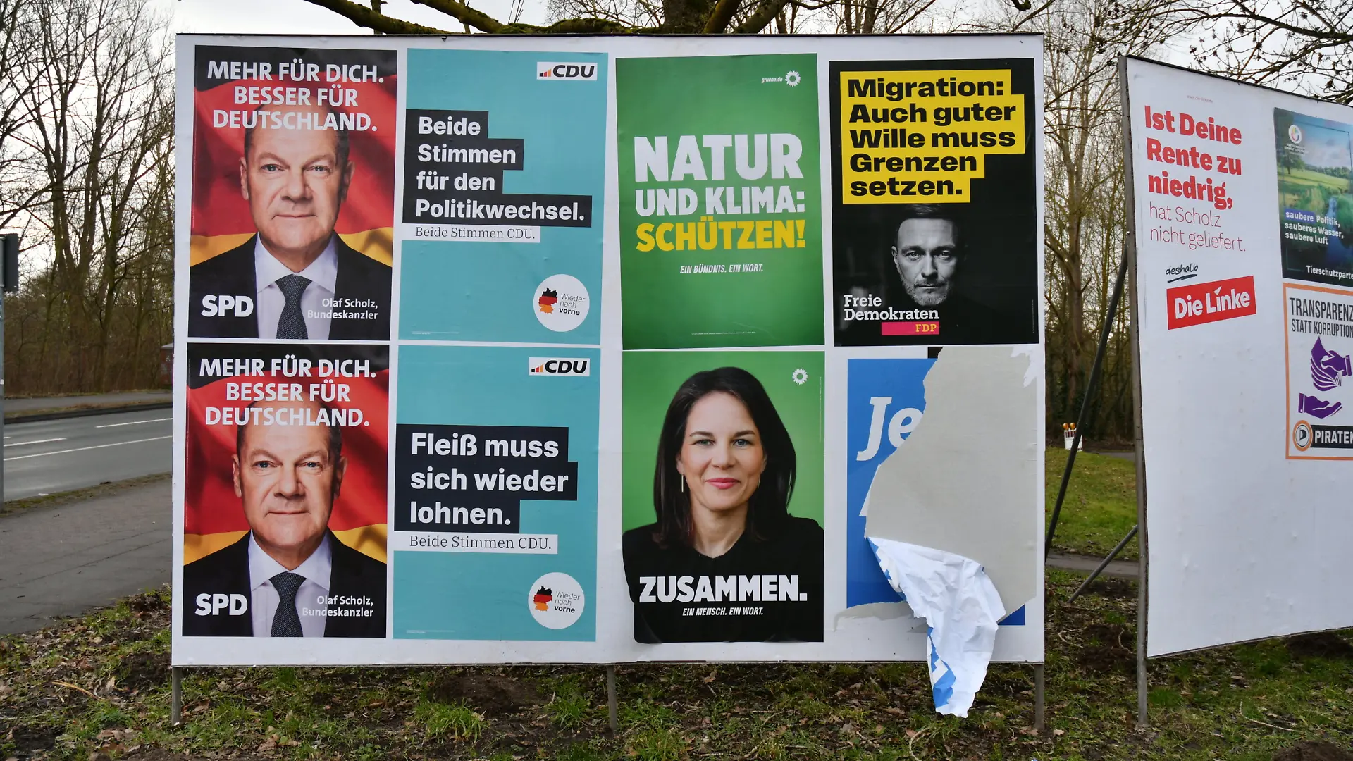 Wahlplakate von verschiedenen Parteien hängen neben einem beschädigten Wahlplakat der AfD.