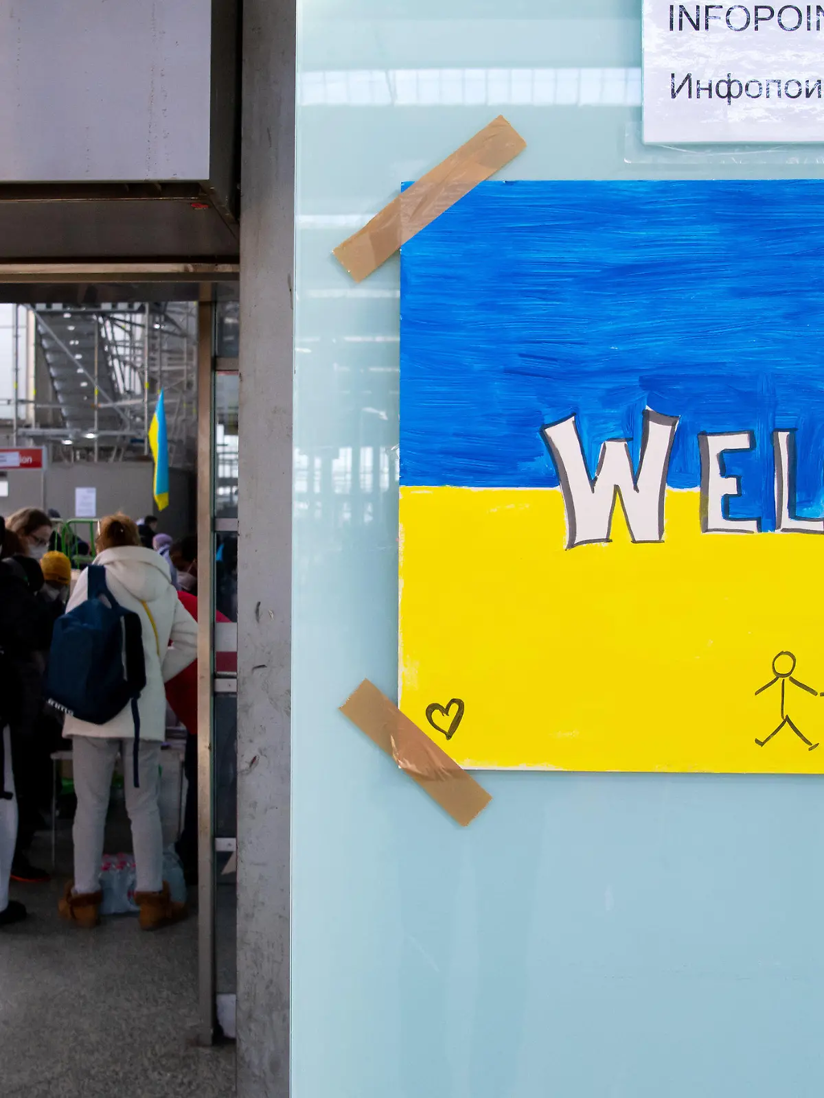 ARCHIV - 09.03.2022, Bayern, München: Ein Schild in den Farben der Ukraine mit der Aufschrift "Welcome" ist am Hauptbahnhof zu sehen. Im Hintergrund werden Flüchtlinge aus der Ukraine nach ihrer Ankunft von Mitarbeitern der Caritas und freiwilligen Helfern empfangen. Doch auch im vermeintlich sicheren Deutschland drohen Gefahren. Hilfsorganisationen warnen, dass geflüchtete Frauen Opfer von Zwangsprostitution oder Ausbeutung werden könnten und  setzen deshalb auf Aufklärung. (zu dpa «Ausbeutung oder gar Gewalt - Wenn geflüchtete Frauen zu Opfern werden») Foto: Sven Hoppe/dpa +++ dpa-Bildfunk +++