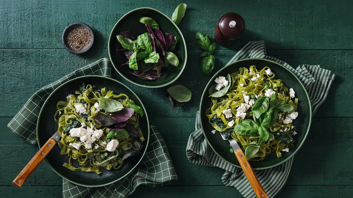 Vegan Gluten-Free Creamy Spinach Pasta and vegan cheese on dark green background