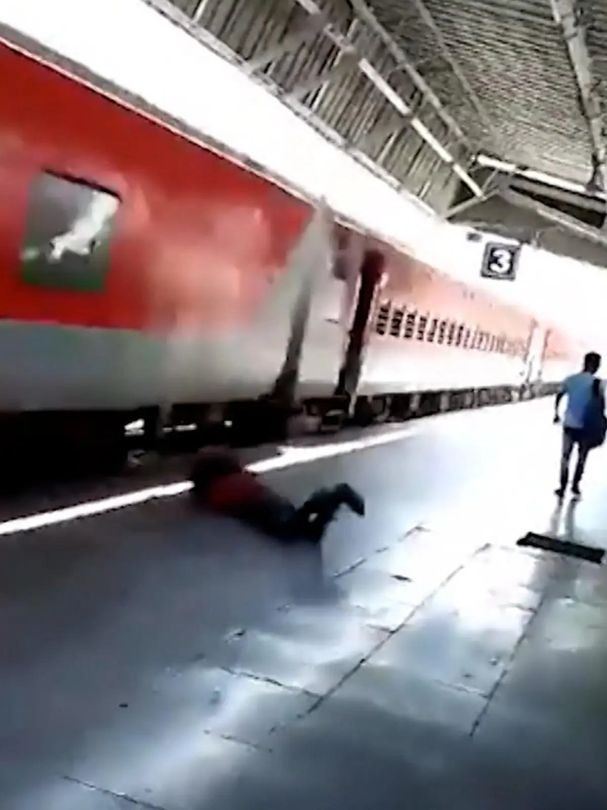 Ein Mann rutscht über einen Bahnsteig, dahinter rauscht ein Zug vorbei.