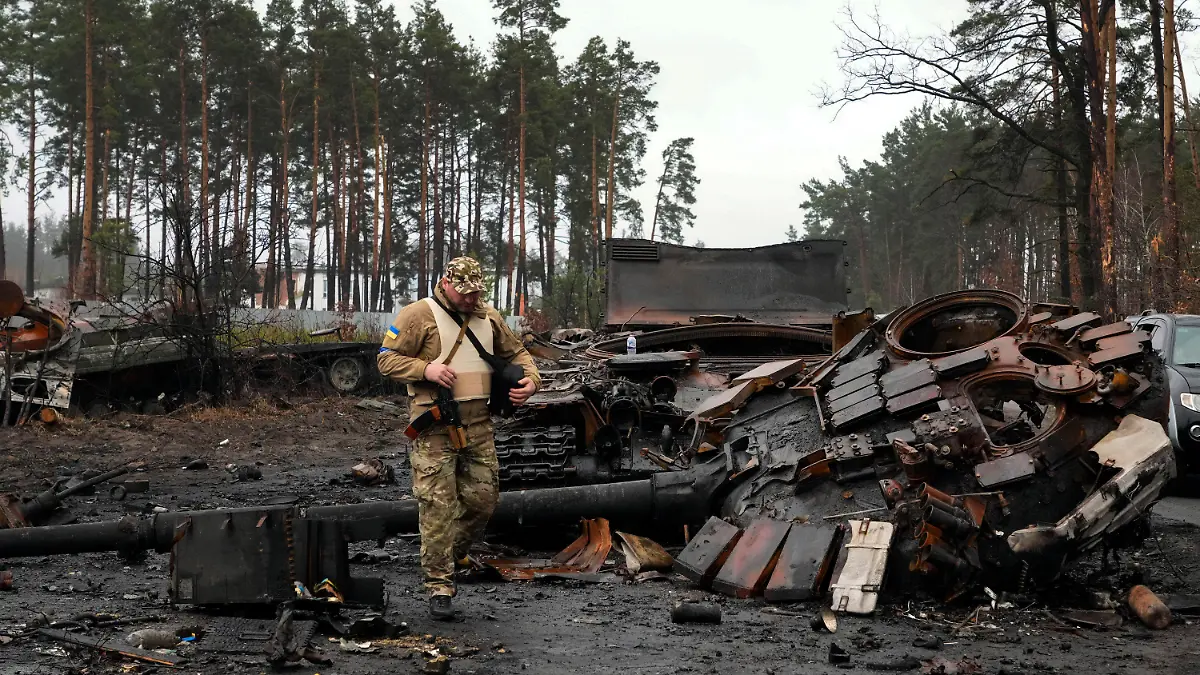 02.04.2022, Ukraine, Dmytriwka: Ein ukrainischer Soldat geht auf einer Straße an einen zerstörten russischen Panzer vorbei. Foto: Efrem Lukatsky/AP/dpa +++ dpa-Bildfunk +++
