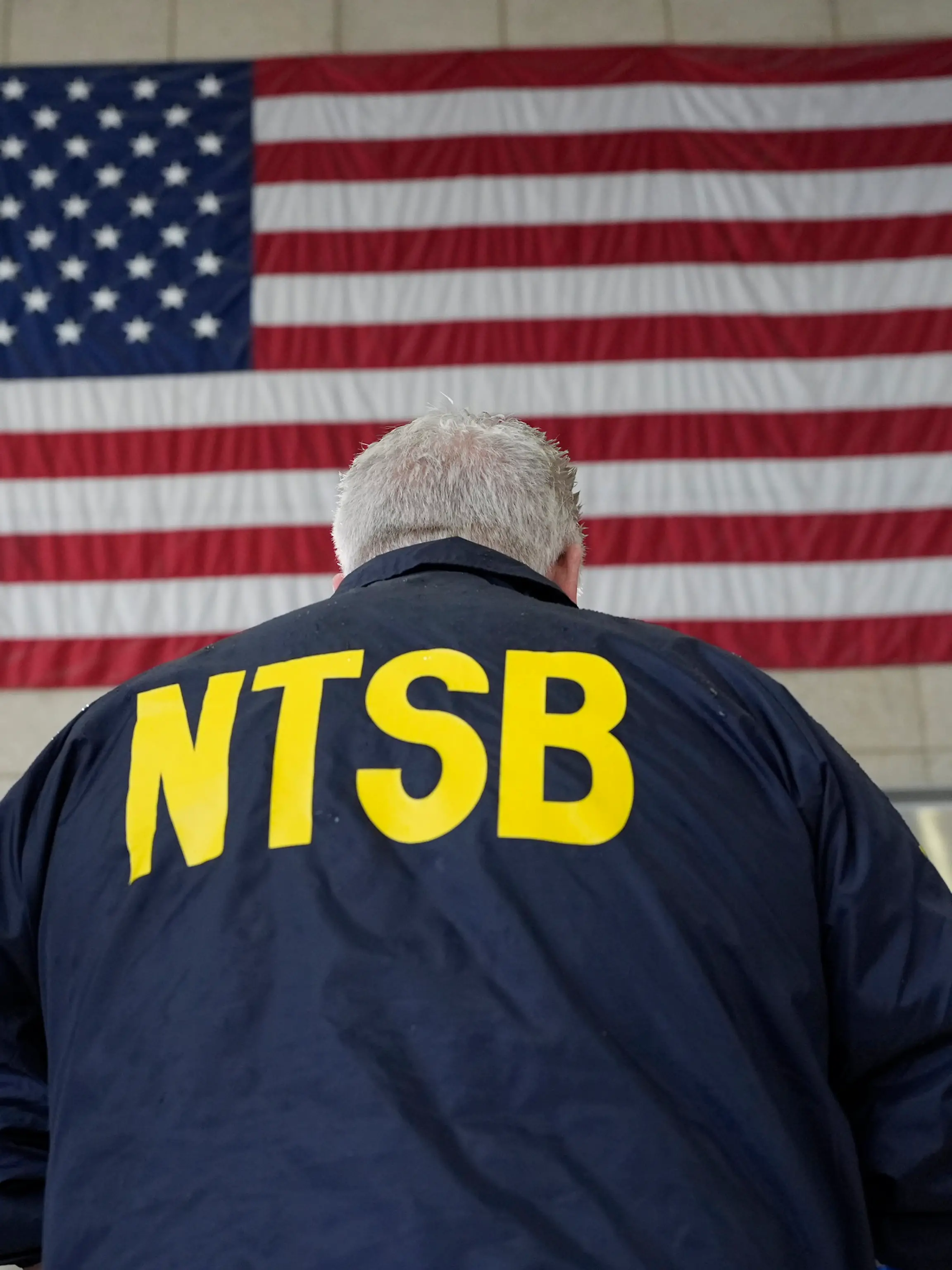 USA, Arlington: Todd Inman, Mitglied des National Transportation Safety Board (NTSB), steht vor einer US-Flagge während er mit Reportern am Ronald Reagan Washington National Airport spricht.