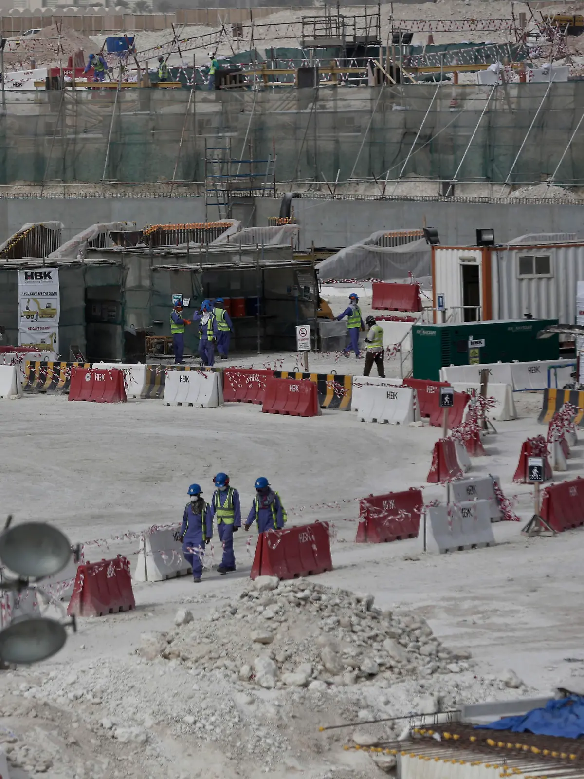 FILE - In this May 4, 2015, file photo taken during a government organized media tour, foreign workers walk between safety barricades at the site of the pitch of the Al-Wakra Stadium that is under construction for the 2022 World Cup in Doha, Qatar. Migrant laborers faced abuse that in some cases amounted to forced labor while working on a stadium that will host soccer matches for the 2022 World Cup in Qatar, a new report released by Amnesty International alleged Thursday, March 31, 2016. (AP Photo/Maya Alleruzzo, File)