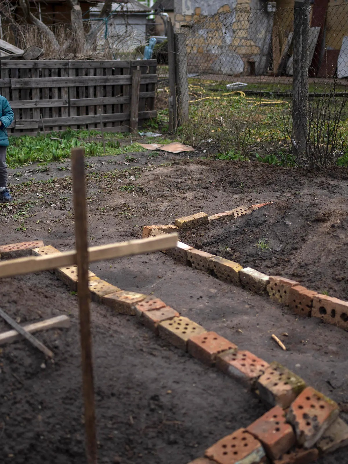 In the courtyard of their house, Vlad Tanyuk, 6, looks at the grave of his mother Ira Tanyuk, who died because of starvation and stress due to the war, in Bucha, on the outskirts of Kyiv, Ukraine, Monday, April 4, 2022. Russia is facing a fresh wave of condemnation after evidence emerged of what appeared to be deliberate killings of dozens if not hundreds of civilians in Ukraine. (AP Photo/Rodrigo Abd)