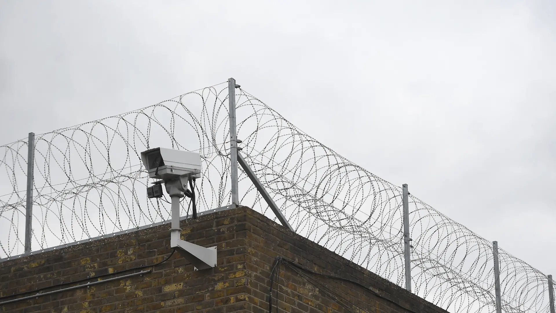 Ein Zaun und eine Überwachungskamera an der Mauer eines Gefängnisses in Großbritannien