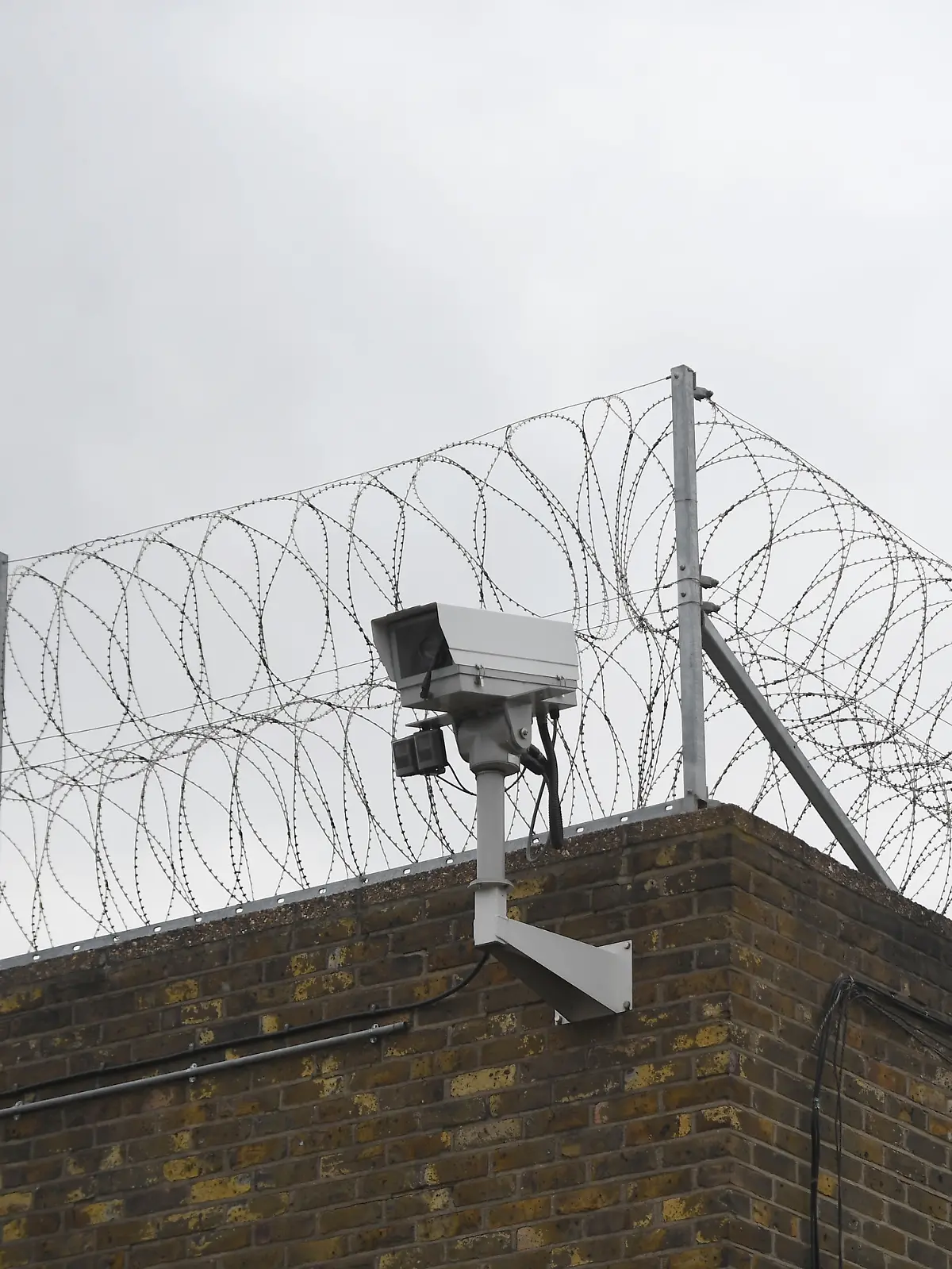 Ein Zaun und eine Überwachungskamera an der Mauer eines Gefängnisses in Großbritannien 