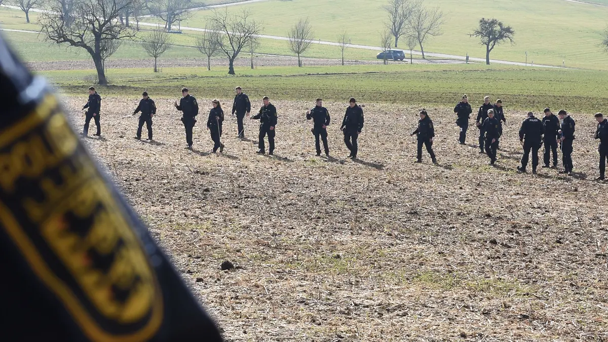 Einsatzkräfte der Polizei suchen ein Gebiet ab.