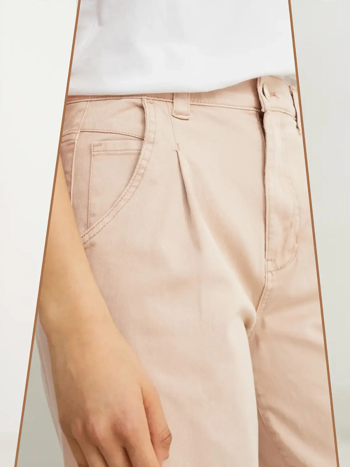 Ein C&A-Modell trägt eine beige Chino mit einem weißen Shirt und einer Denim-Weste.