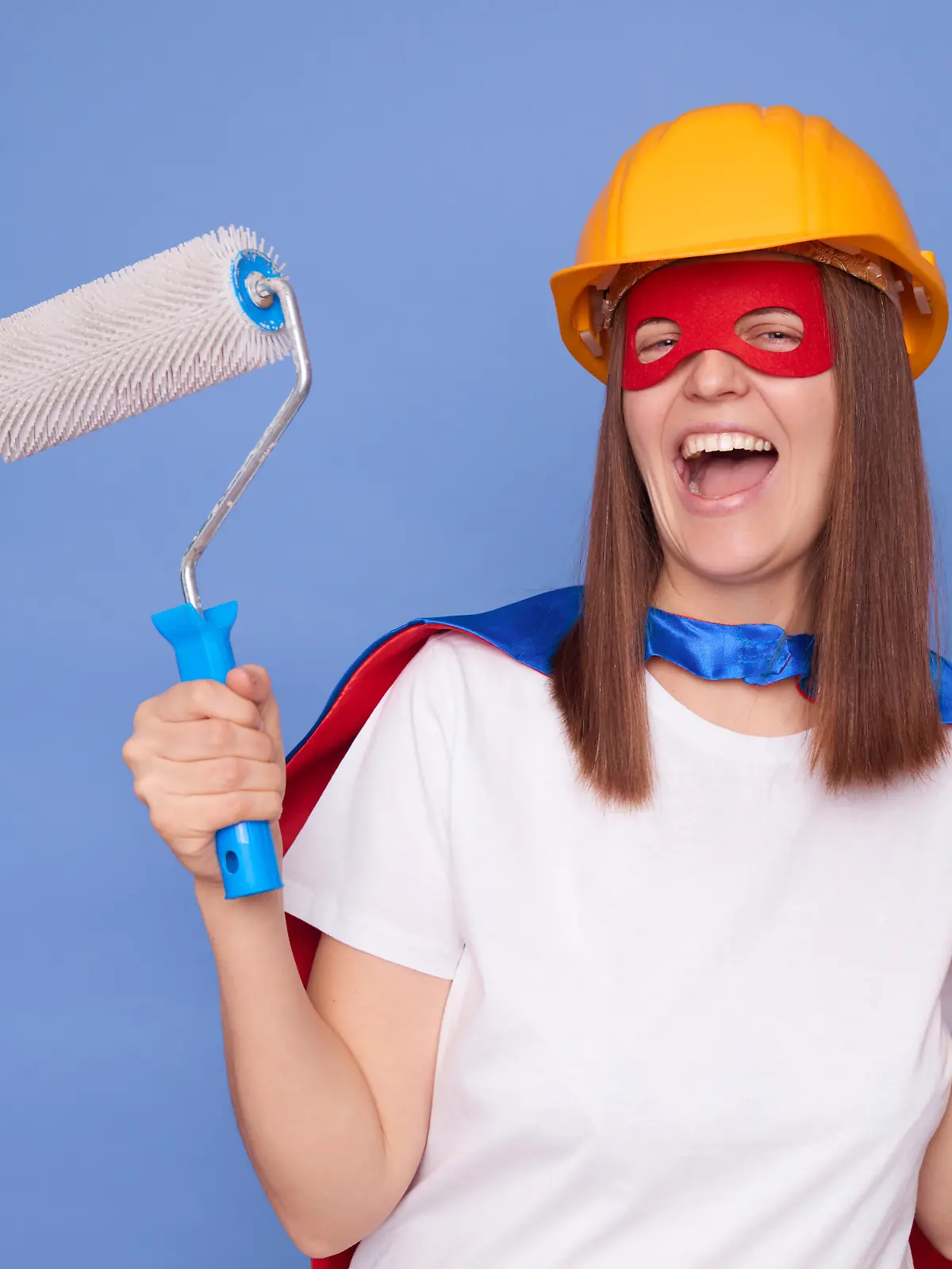 Eine Frau als Superheldin verkleidet hält Maler-Utensilien in der Hand.