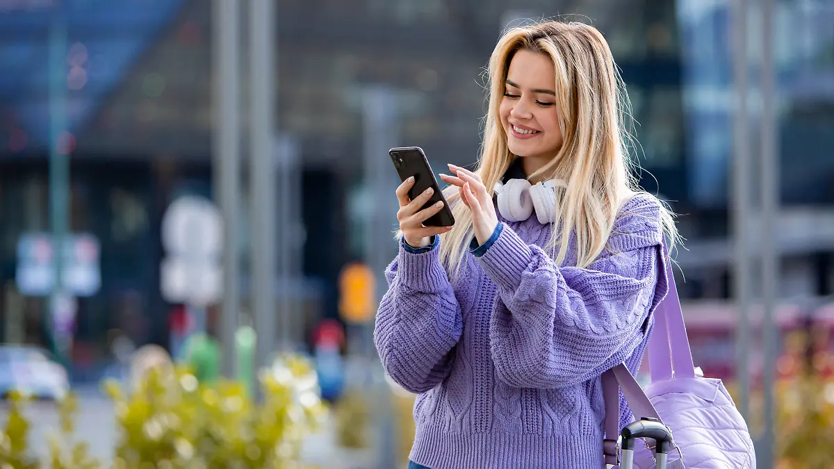 Eine junge Frau schaut gut gelaunt auf ihr Handy.