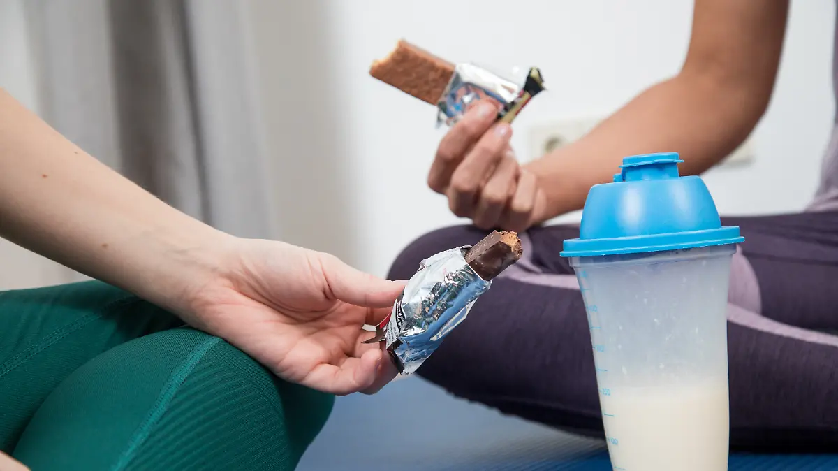 Zwei Frauen essen und trinken nach einem Workout proteinhaltige Lebensmittel (gestellte Szene).
