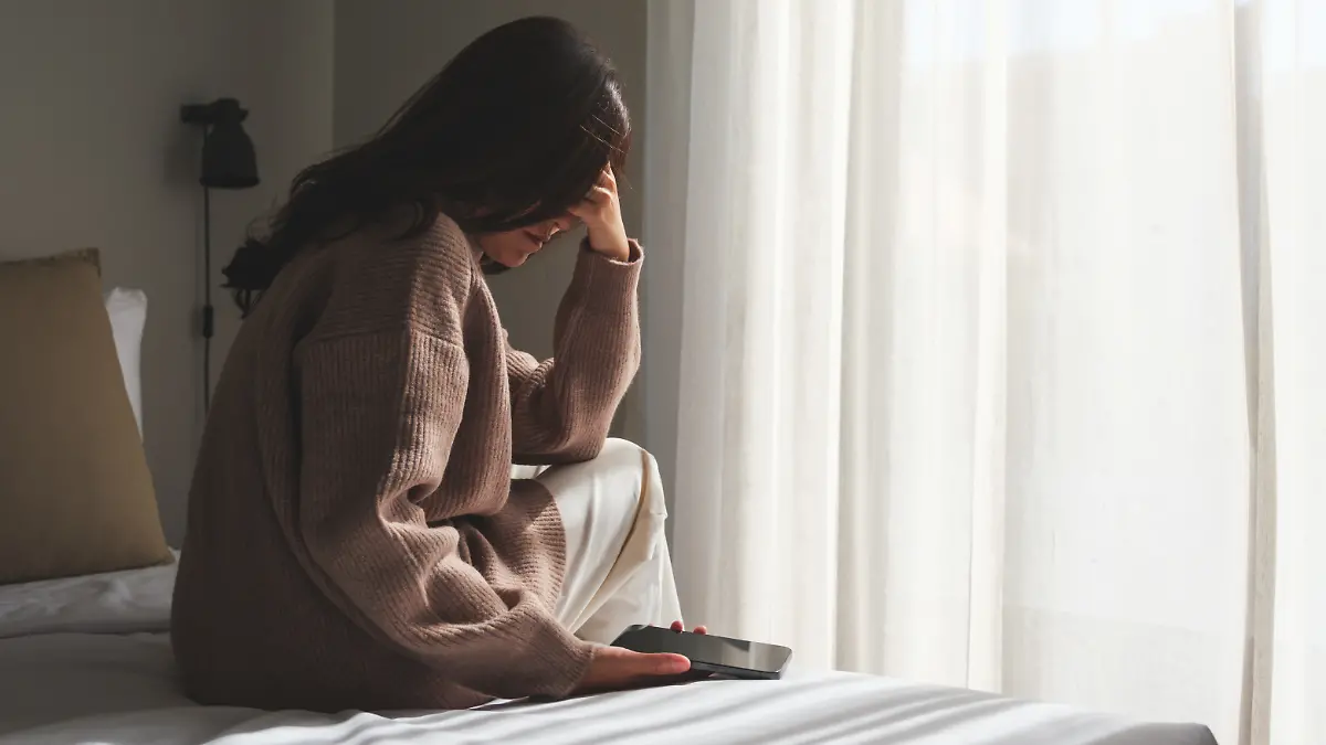 Frau sitzt mit Telefon auf dem Bett
