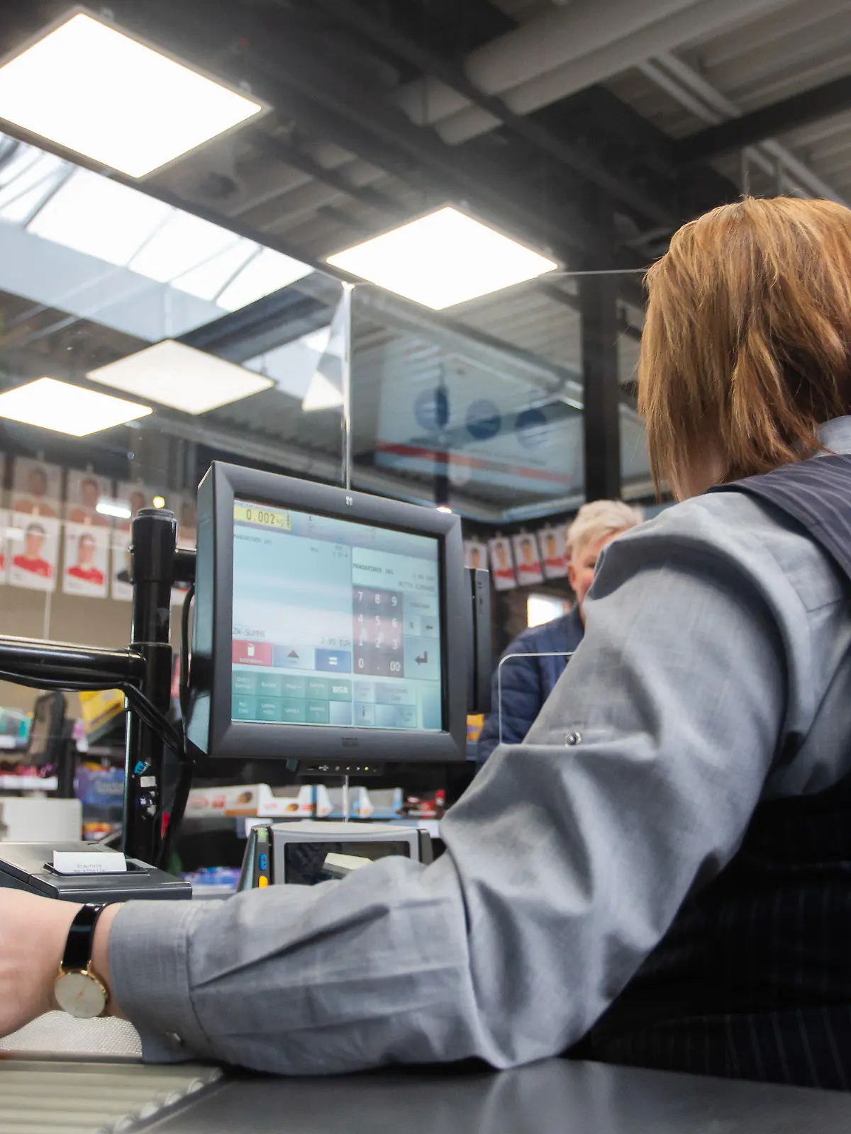 25.03.2020, Baden-Württemberg, Göppingen: An einer Kasse in einem Supermarkt wird die Kassiererin mit einer Plexiglasscheibe, einem sogenannten "Spuckschutz", geschützt. Foto: Tom Weller/dpa +++ dpa-Bildfunk +++