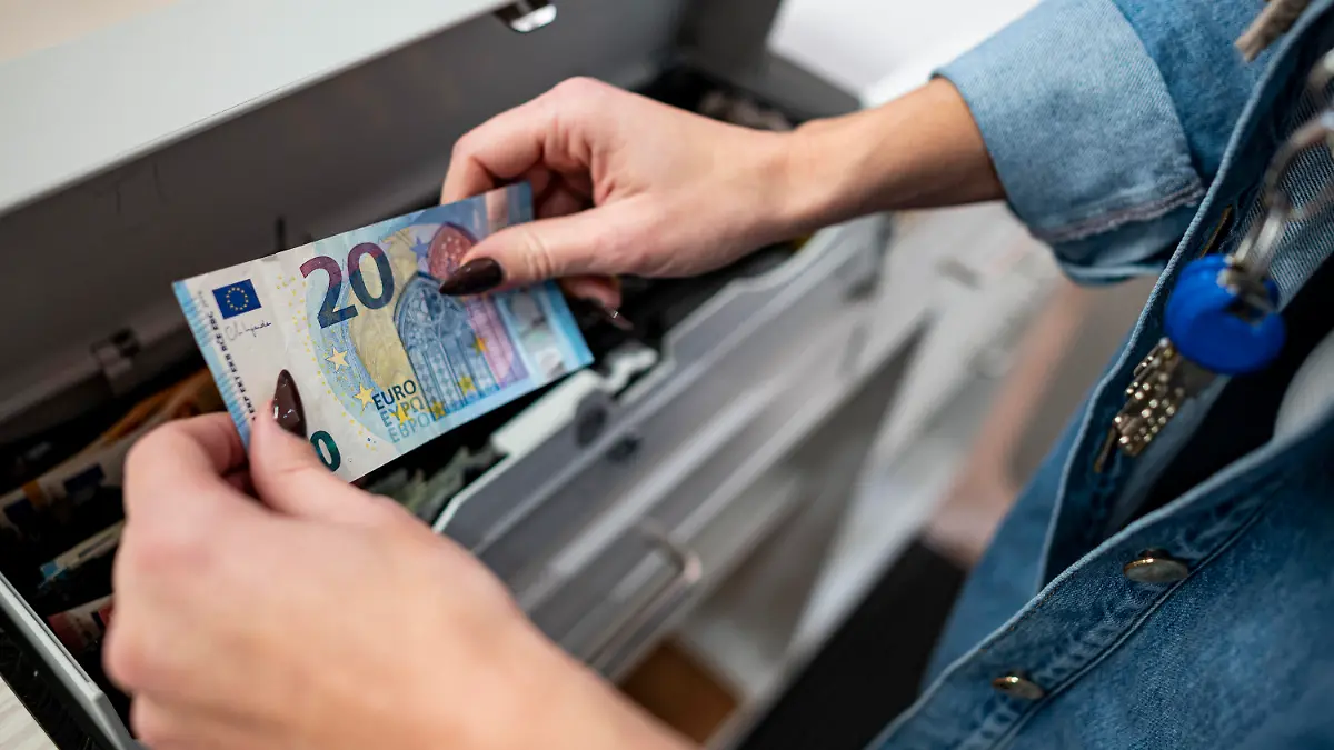 PRODUKTION - 02.03.2022, Berlin: Eine Mitarbeiterin legt Geld in die Kasse in einem Bekleidungsladen in einem Einkaufscenter in Berlin-Marzahn. Das ifo Institut veröffentlicht am 25.03.2022 seinen monatlichen Geschäftsklimaindex. Foto: Fabian Sommer/dpa +++ dpa-Bildfunk +++