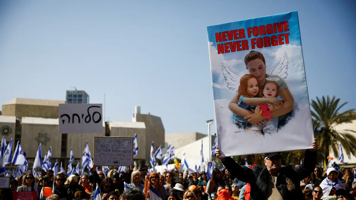 Ein Mann hält beim Trauerzug für Shiri Bibas (32) und ihre beiden Kinder Kfir (9 Monate) und Ariel (4) ein Schild mit einem Bild der Familie hoch. 