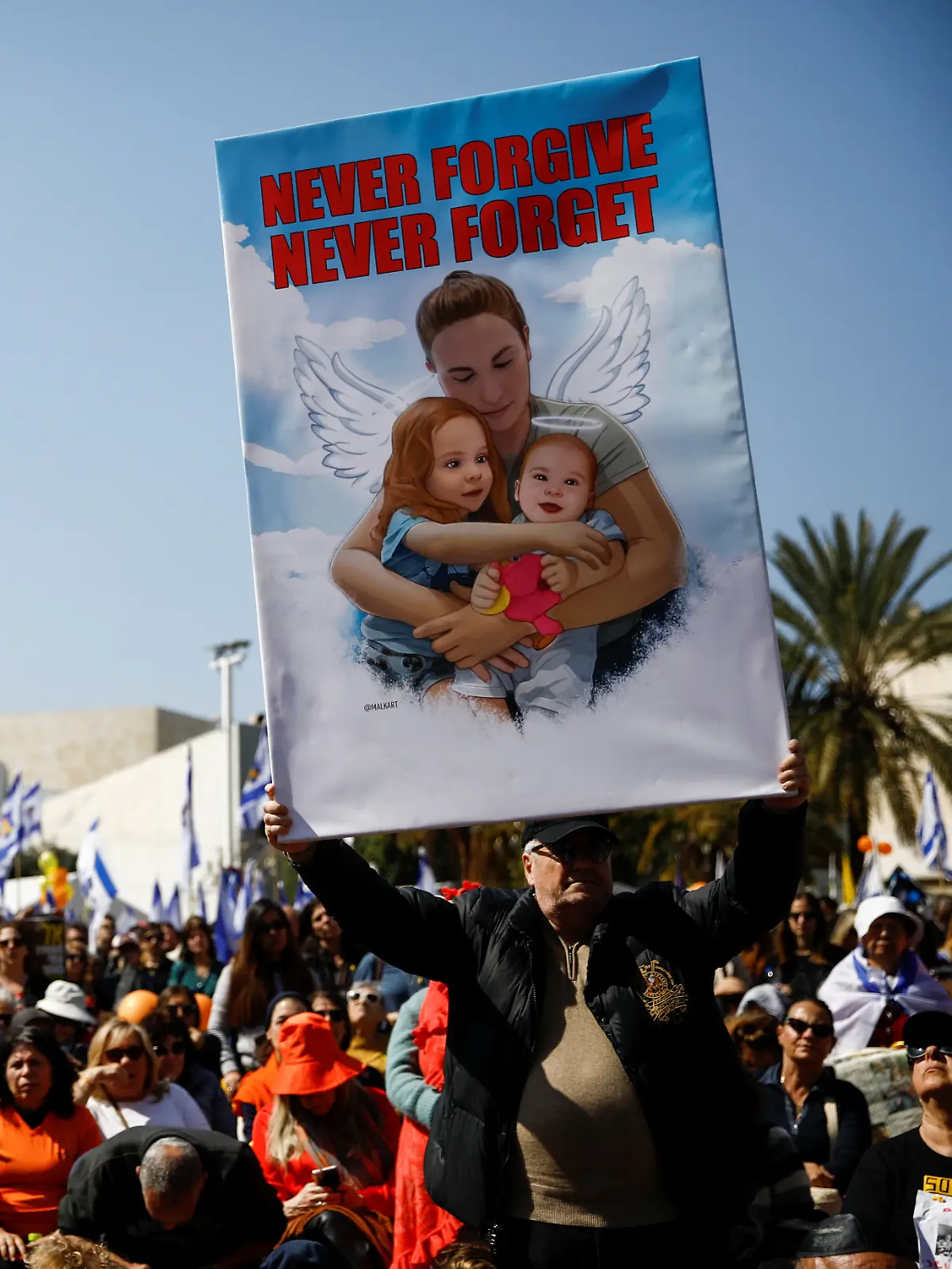 Ein Mann hält beim Trauerzug für Shiri Bibas (32) und ihre beiden Kinder Kfir (9 Monate) und Ariel (4) ein Schild mit einem Bild der Familie hoch. 