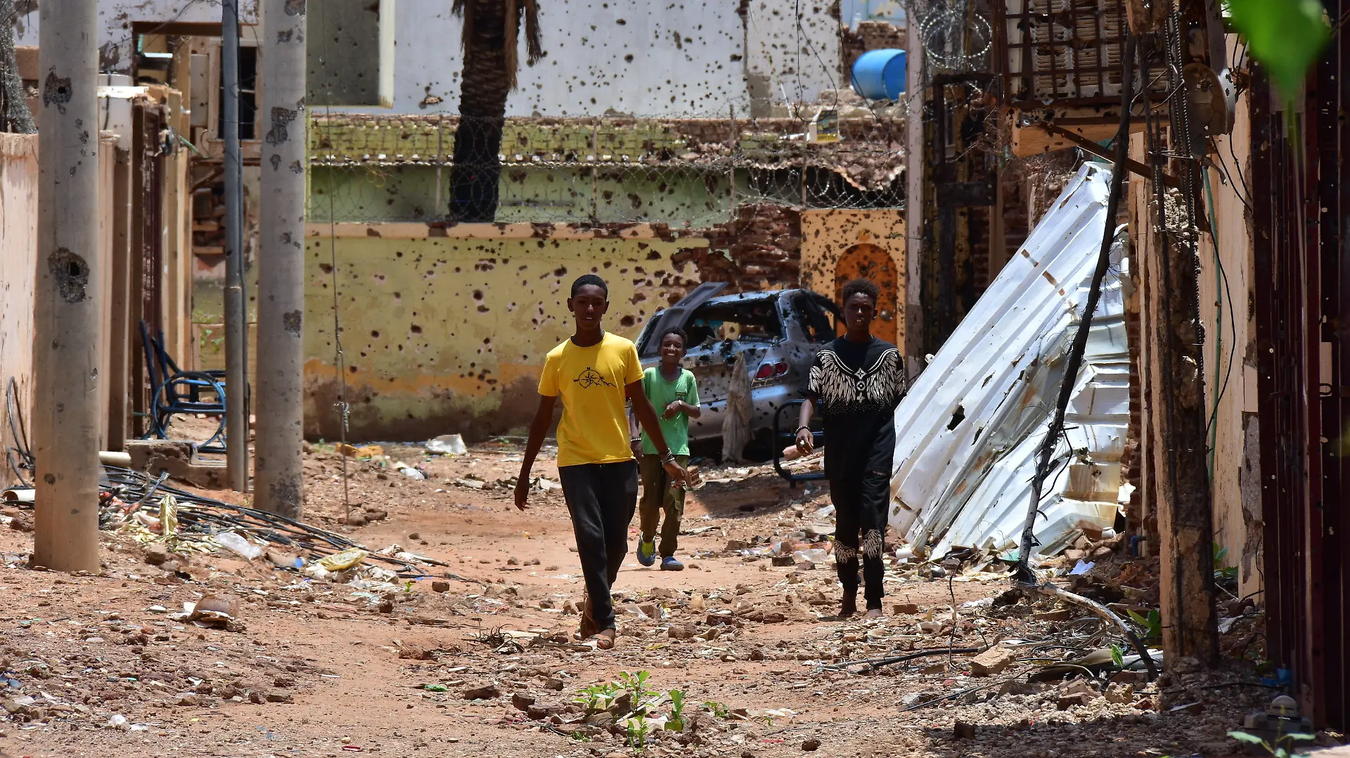 Jugendliche gehen auf einer von Zerstörungen gezeichneten Straße. Im Sudan herrscht seit 22 Monaten ein blutiger Machtkampf. Der Konflikt hat die nach UN-Angaben weltweit größte Flüchtlingskrise ausgelöst.