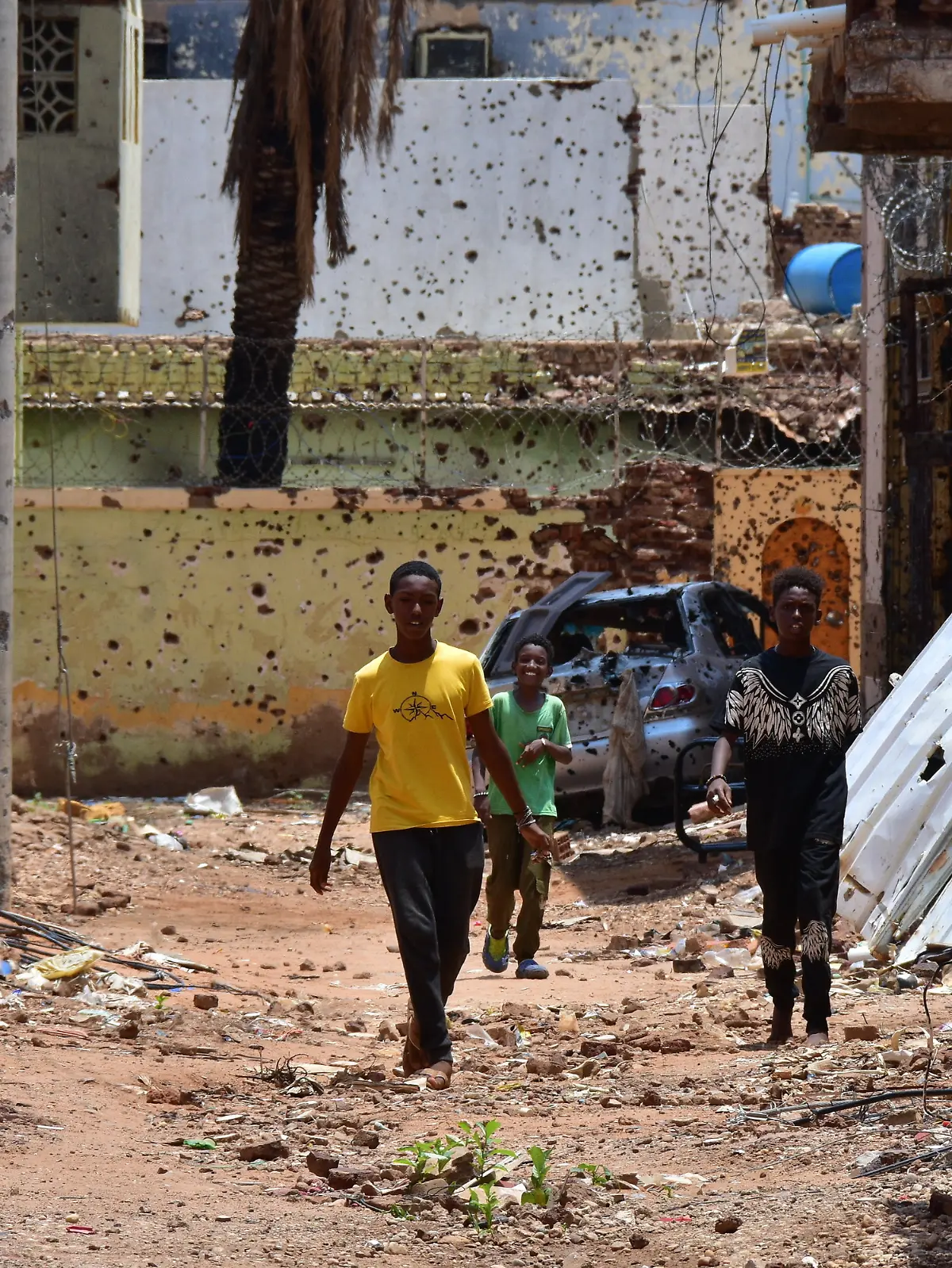 Jugendliche gehen auf einer von Zerstörungen gezeichneten Straße. Im Sudan herrscht seit 22 Monaten ein blutiger Machtkampf. Der Konflikt hat die nach UN-Angaben weltweit größte Flüchtlingskrise ausgelöst. 