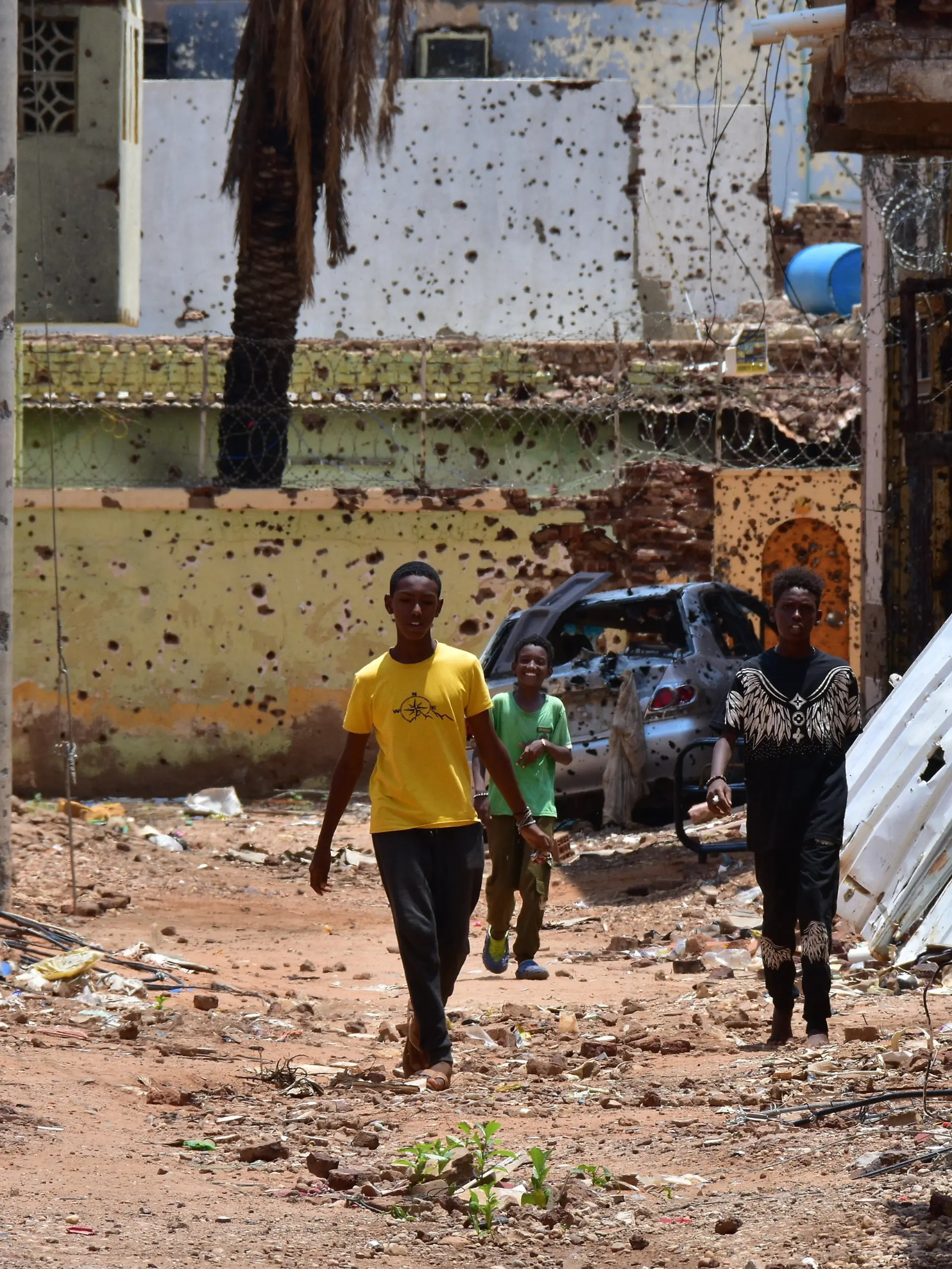 Jugendliche gehen auf einer von Zerstörungen gezeichneten Straße. Im Sudan herrscht seit 22 Monaten ein blutiger Machtkampf. Der Konflikt hat die nach UN-Angaben weltweit größte Flüchtlingskrise ausgelöst. 
