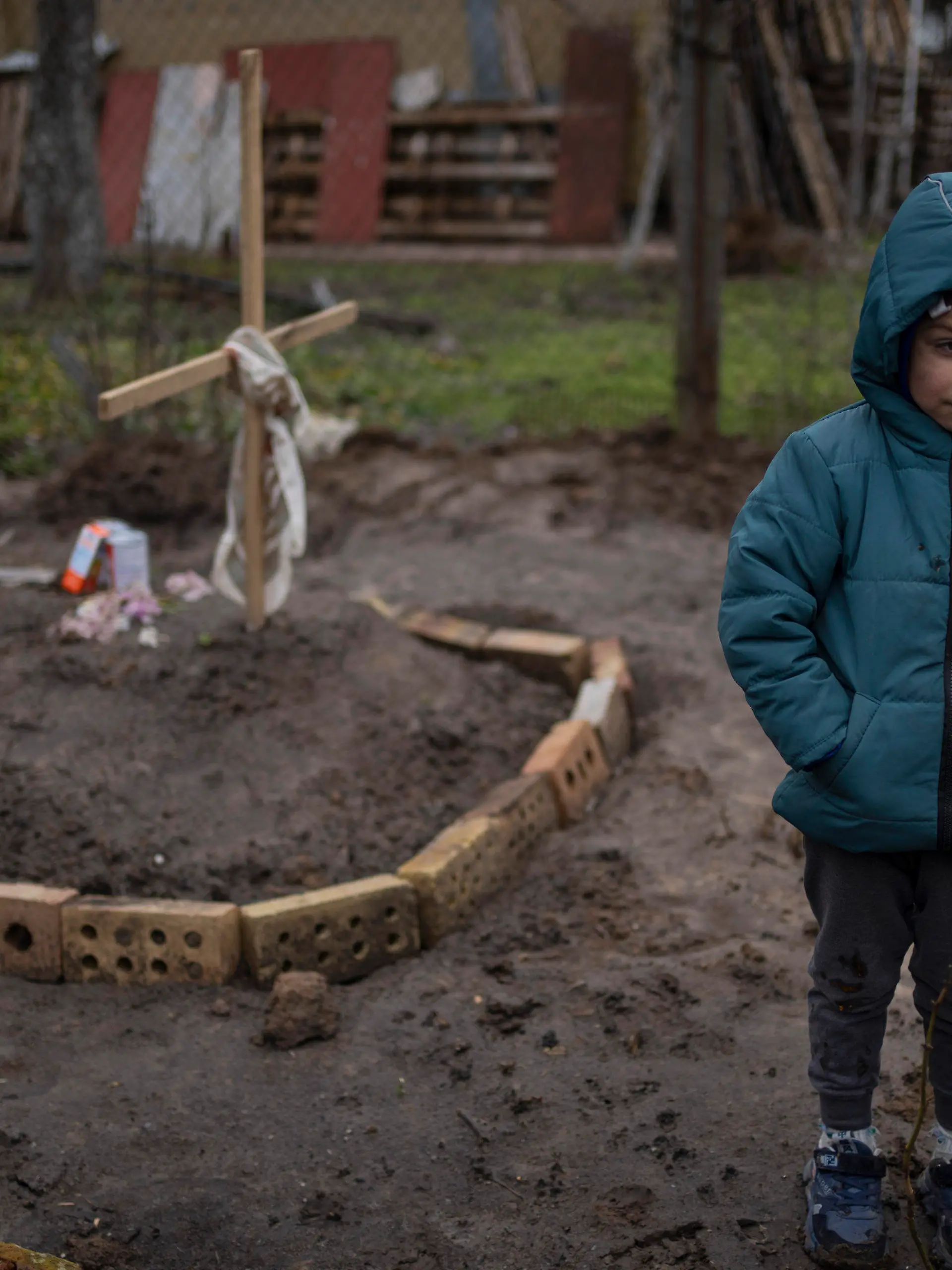 In the courtyard of their house, Vlad Tanyuk, 6, stands near the grave of his mother Ira Tanyuk, who died because of starvation and stress due to the war, on the outskirts of Kyiv, Ukraine, Monday, April 4, 2022. (AP Photo/Rodrigo Abd)