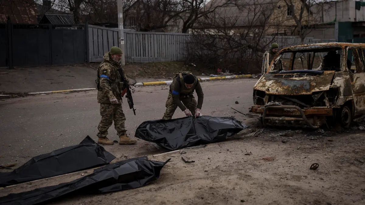 05.04.2022, Ukraine, Butscha: *** ATTENTION EDITORS GRAPHIC CONTENT *** Zwei ukrainische Soldaten bergen die Überreste von vier getöteten Zivilisten aus einem verkohlten Fahrzeug in Butscha. Die Gräueltaten an Bewohnern der Stadt Butscha sind nach Angaben des ukrainischen Präsidenten Selenskyj kein Einzelfall. Foto: Felipe Dana/AP/dpa - *** ATTENTION EDITORS GRAPHIC CONTENT *** +++ dpa-Bildfunk +++