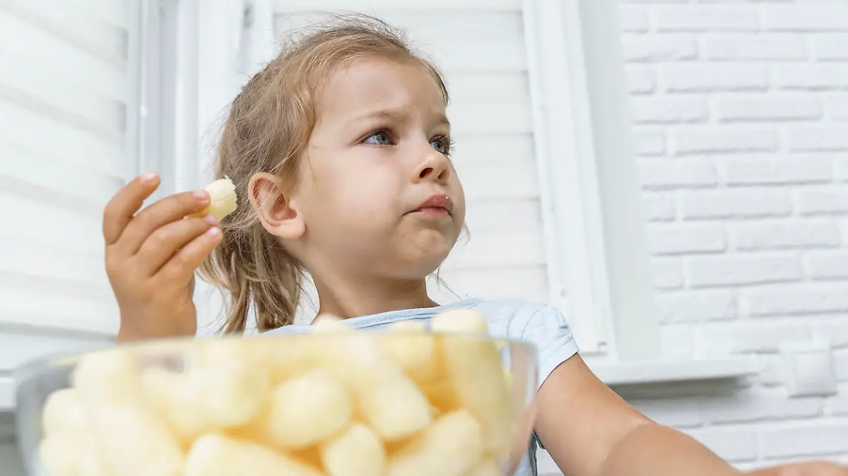 child eating corn sticks at the kitchen table