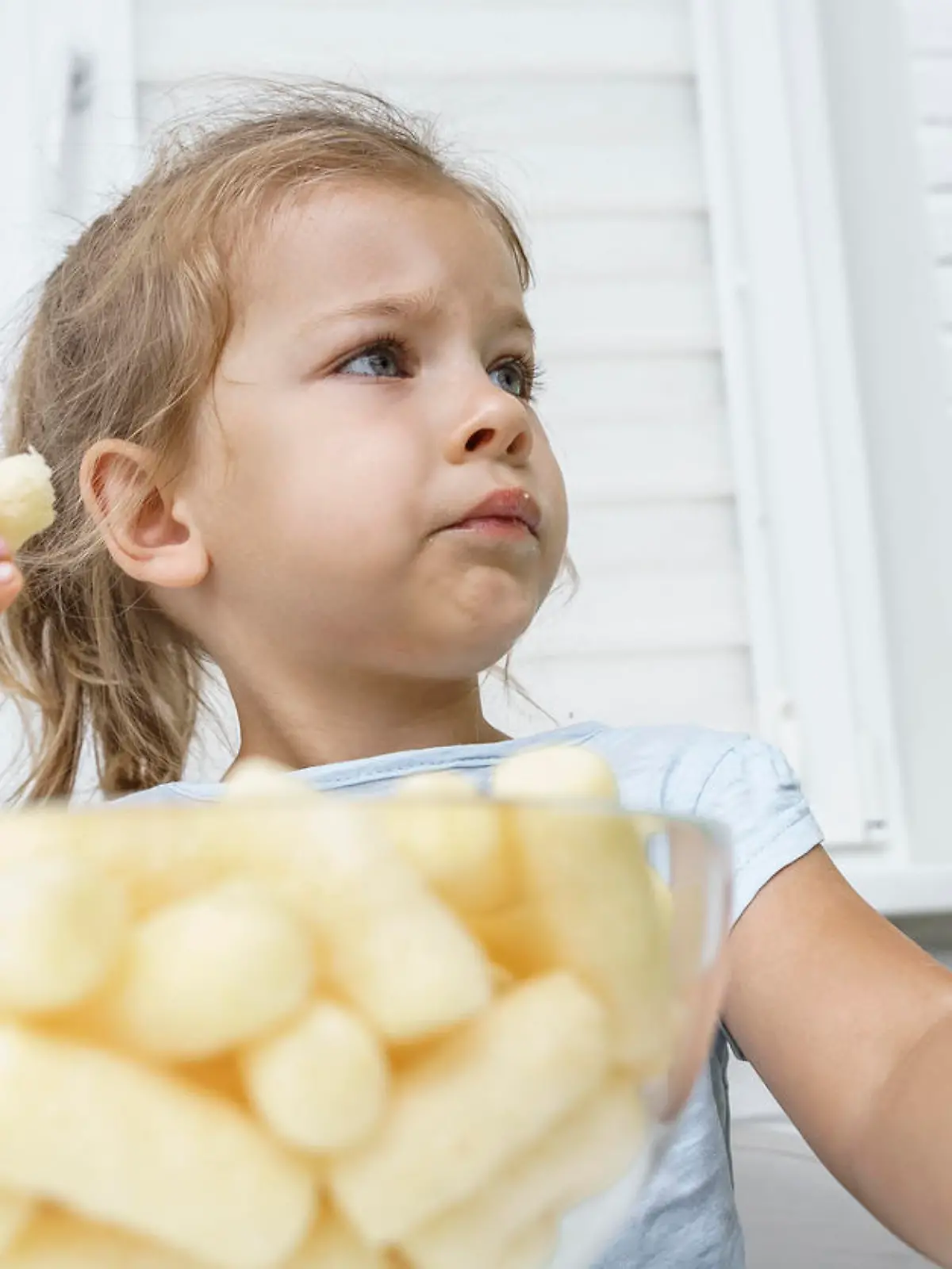 child eating corn sticks at the kitchen table