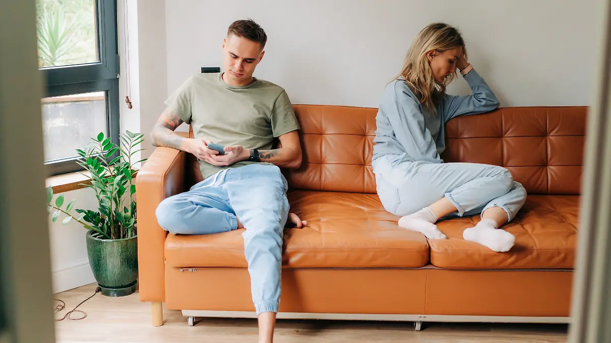 Ein Paar hat sich gestritten und sitzt nebeneinander auf dem Sofa.